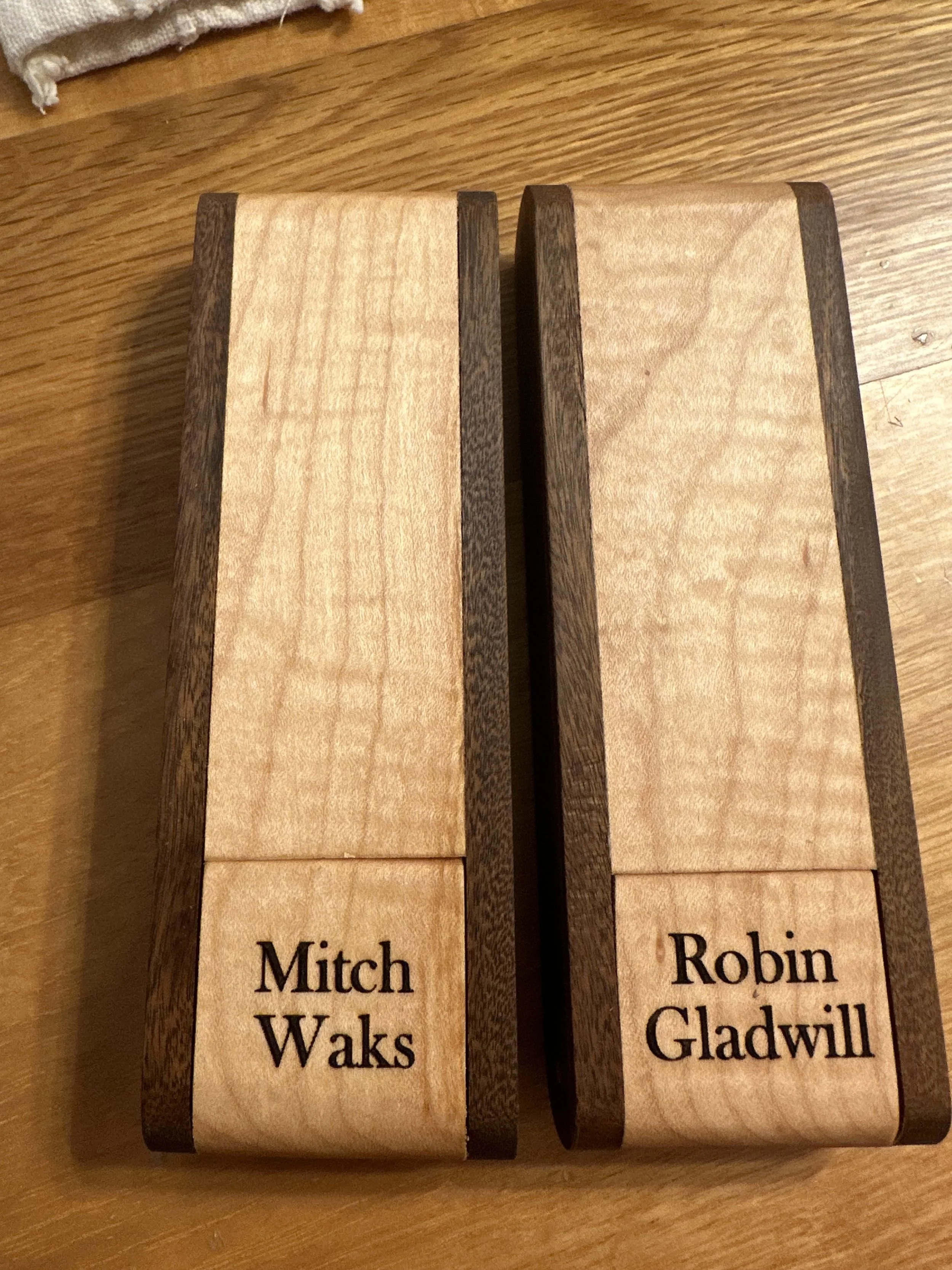 Wooden table with two engraved wooden name plaques, one reads 'Mitch Waks' and the other reads 'Robin Gladwill'.