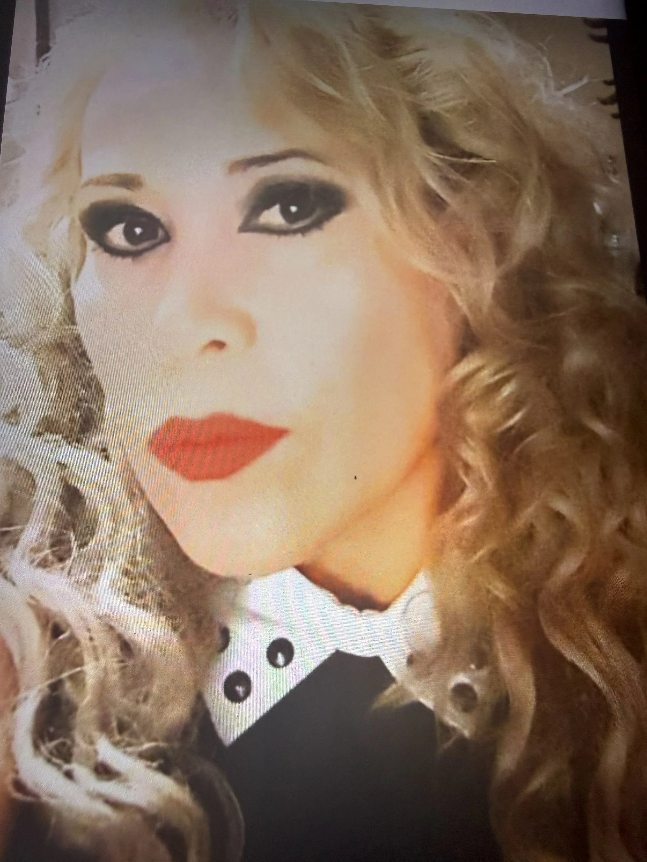 Retrato de la propietaria con maquillaje llamativo y cabello rizado, con fondo negro y detalles dorados.