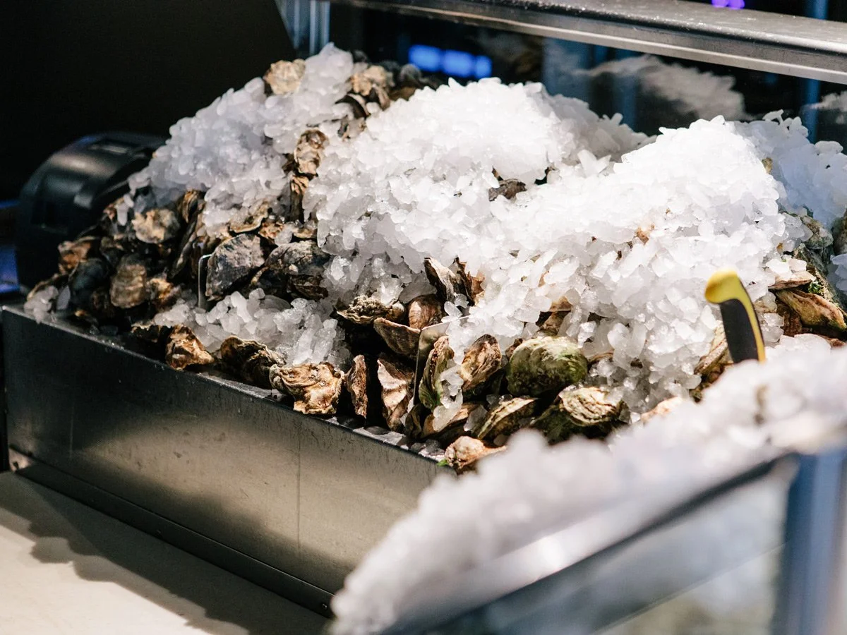 A display of fresh oysters on ice at a seafood market or restaurant.