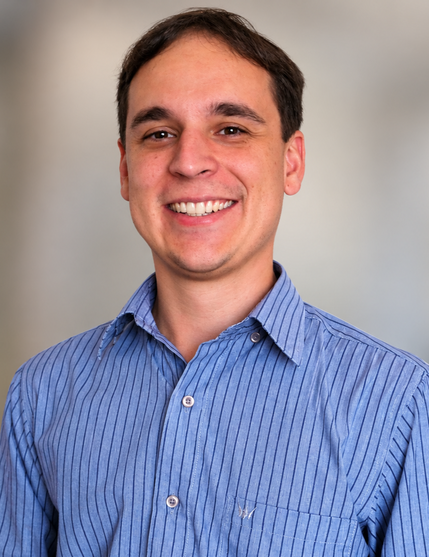 Smiling man in a blue striped button-down shirt posing for a professional headshot