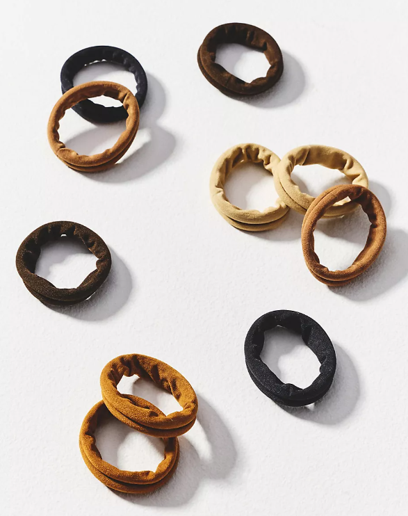 Eight colorful hair ties on a white surface, arranged in a scattered pattern.