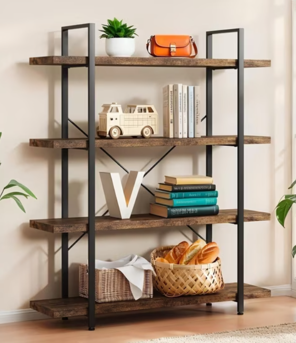 A black metal and wood bookshelf with four shelves, decorated with a potted plant, orange handbag, toy van, books, a decorative white 'V' letter, a wicker basket with bread, and a small woven hamper, with potted plants on each side.