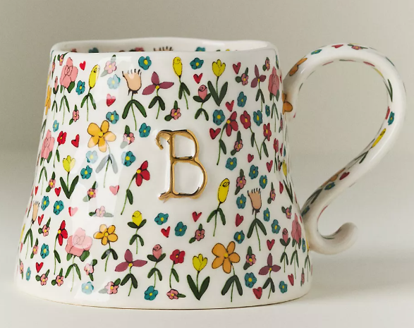 A white ceramic mug with a colorful floral pattern and a gold letter B on the side.