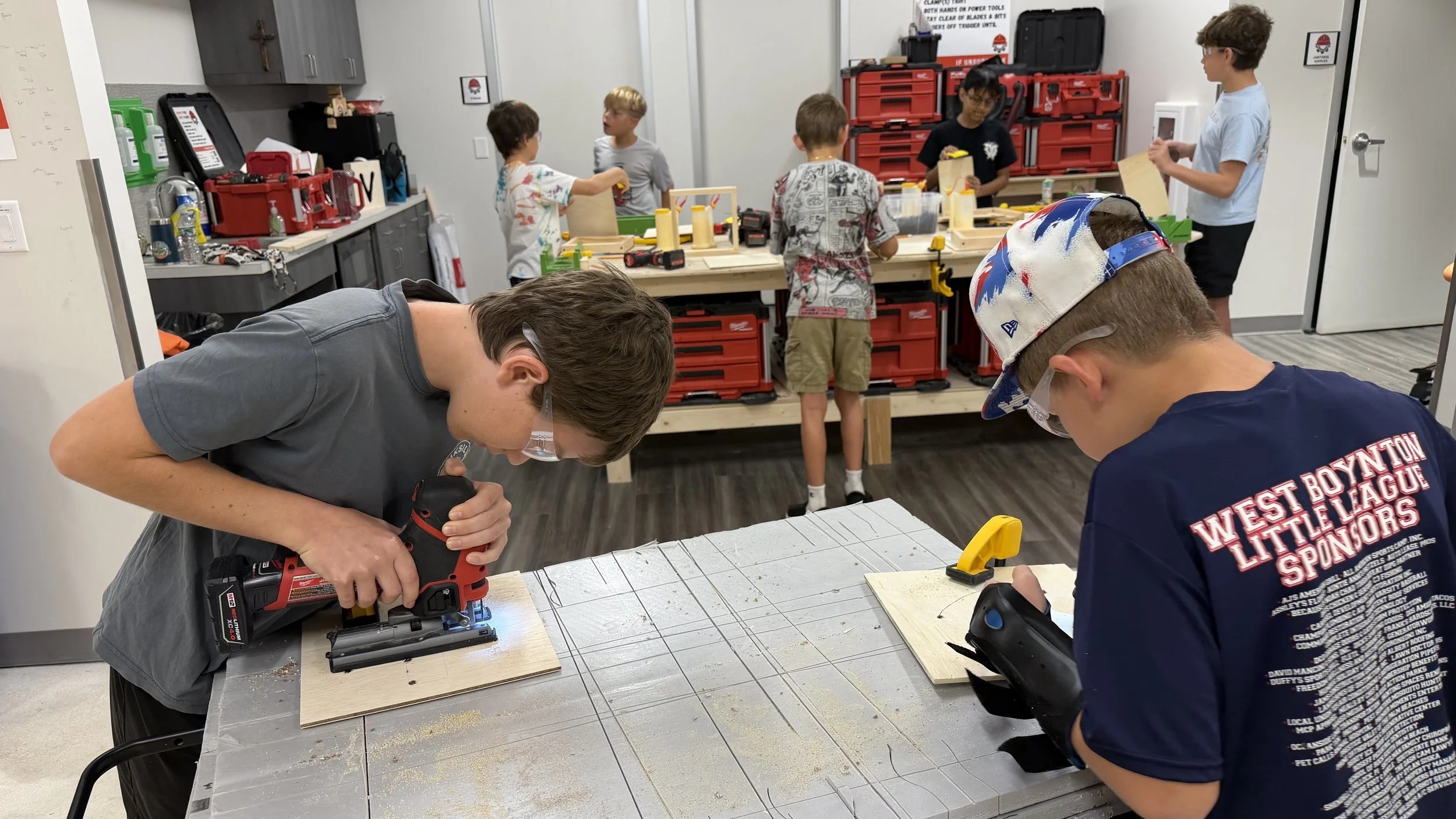 Group of boys and children working on woodworking projects in a classroom or workshop during the daytime.