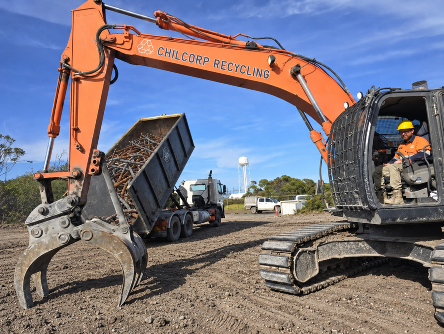 Chilcorp excavator beside a scrap-filled bin