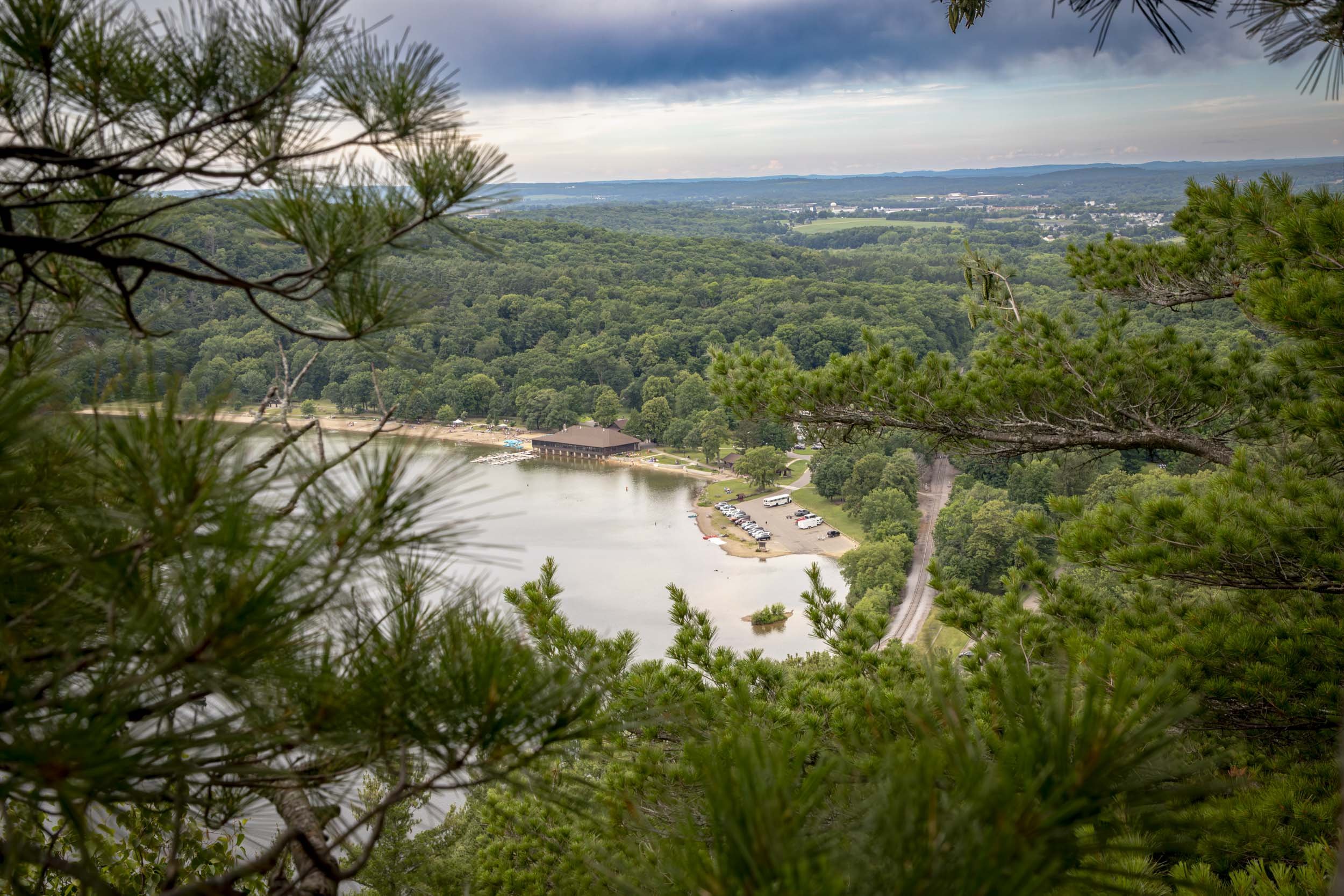 View through pine branches toward a beach and wooded landscape at Devil’s Lake.