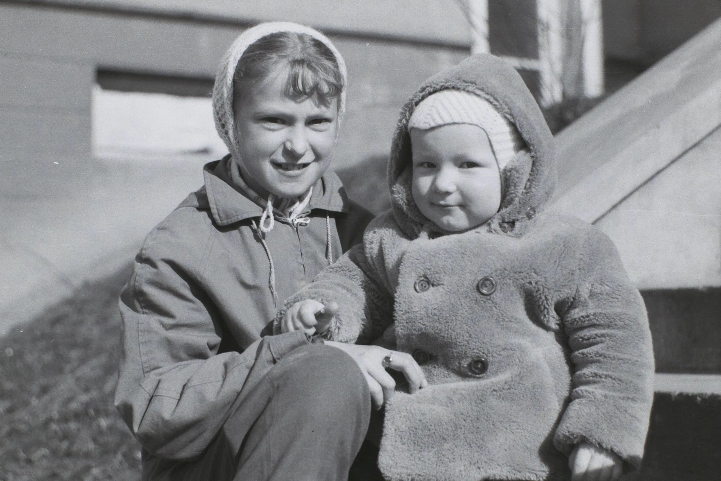Black-and-white photograph of two children sitting together outdoors.