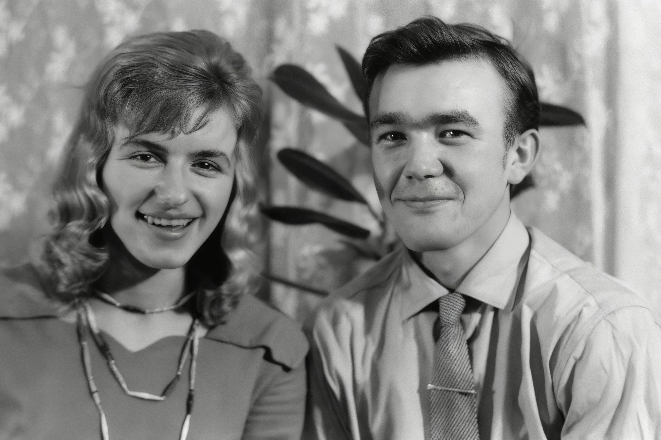 Black-and-white portrait of a smiling woman and man seated together indoors.