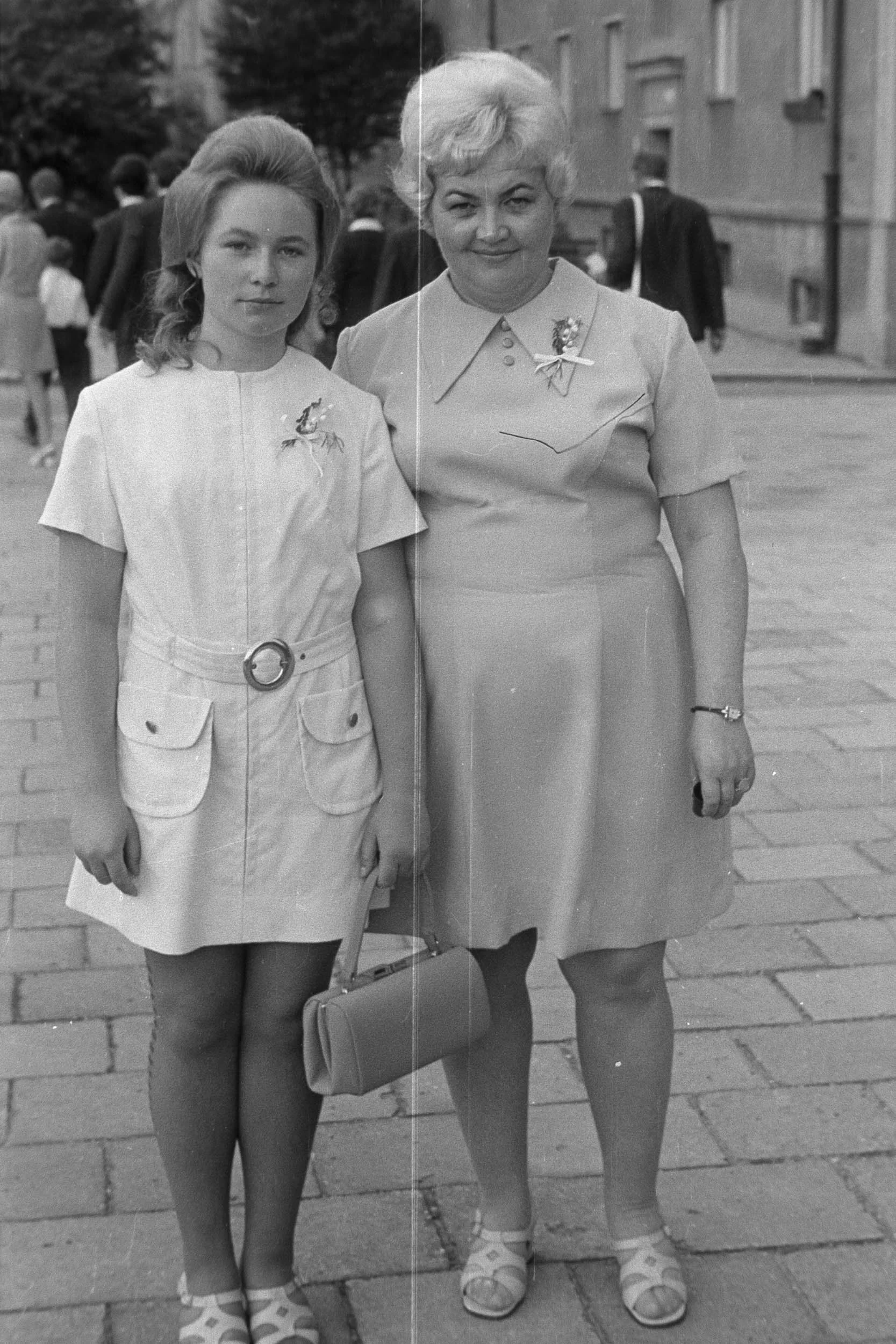 Restored black-and-white photograph of two women standing side by side on a paved street.