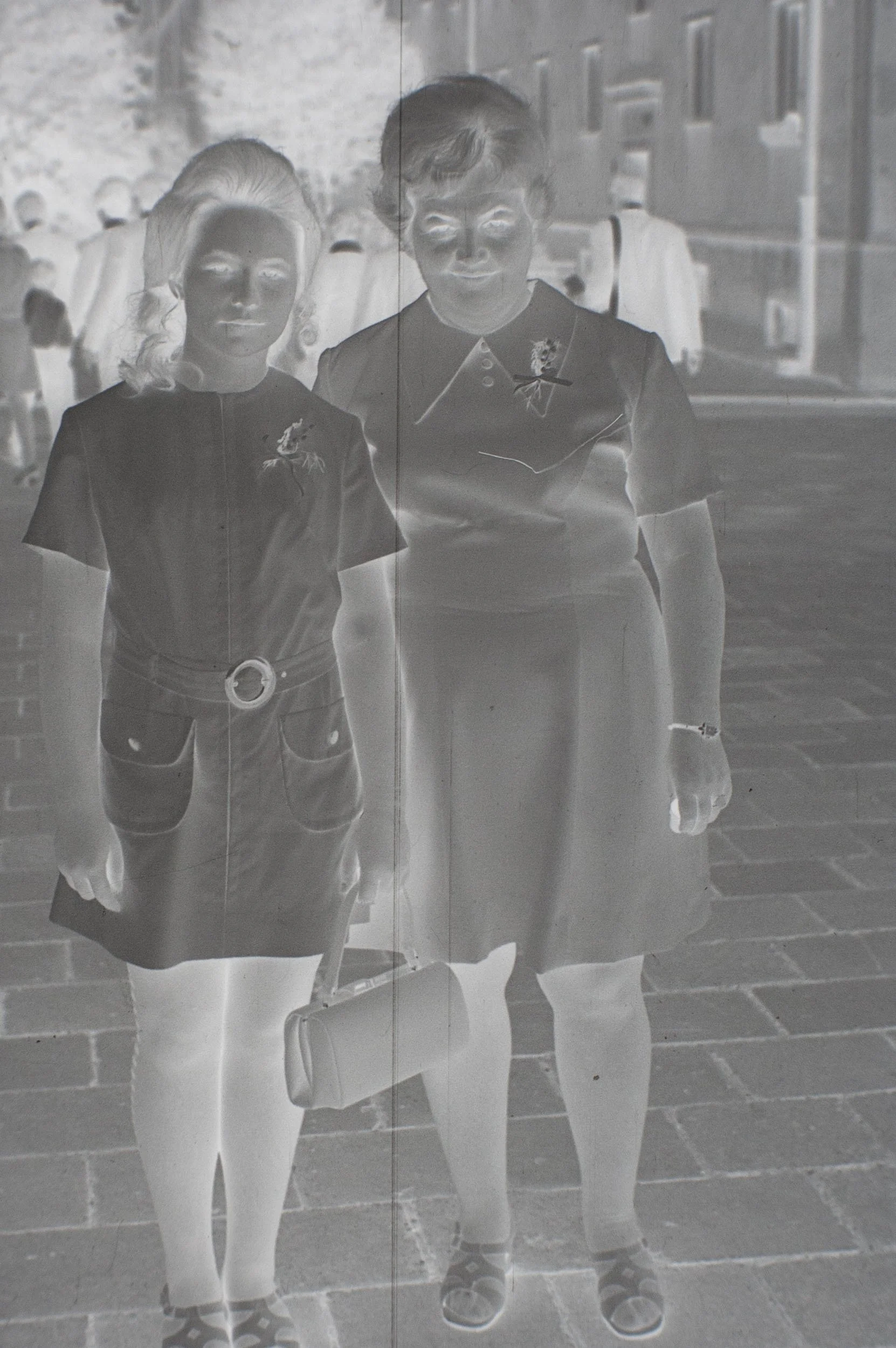 Original photographic negative of two women standing side by side on a paved street.