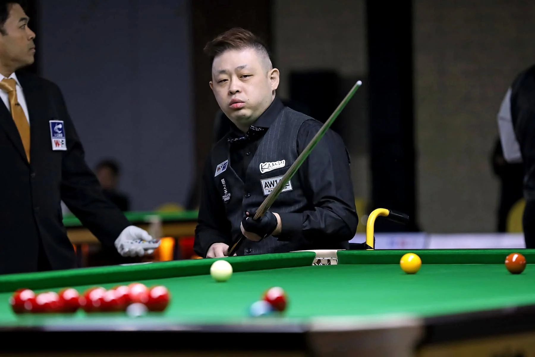 Snooker player standing at the table wearing an AW147 cue badge