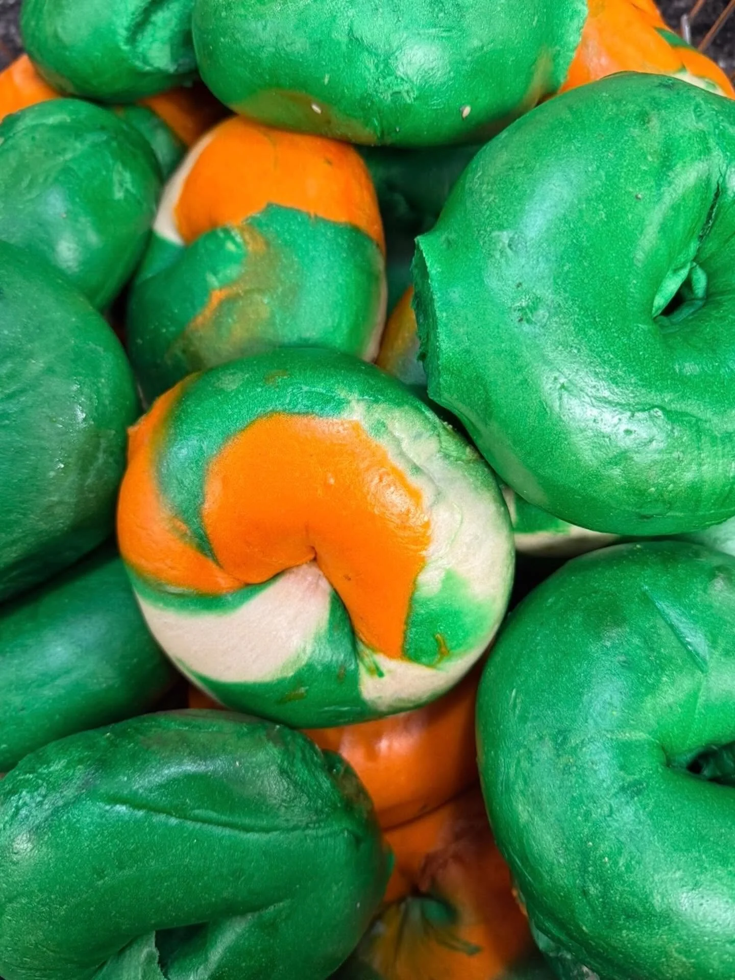 Close-up image of several green and orange bell peppers piled together.