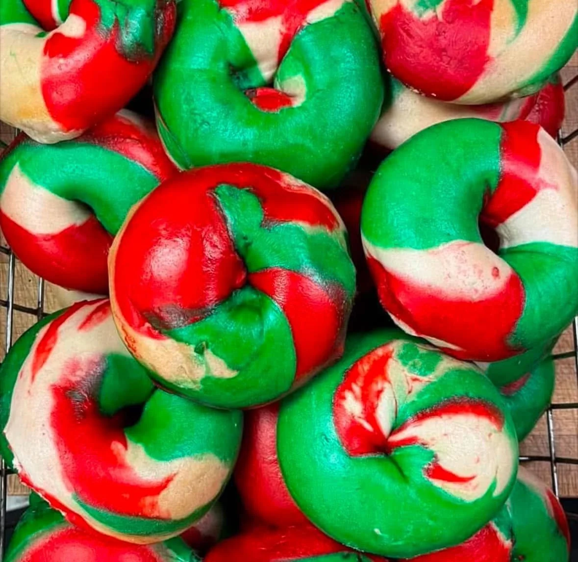 Colorful bagels with red, green, and white swirls in a wire basket.
