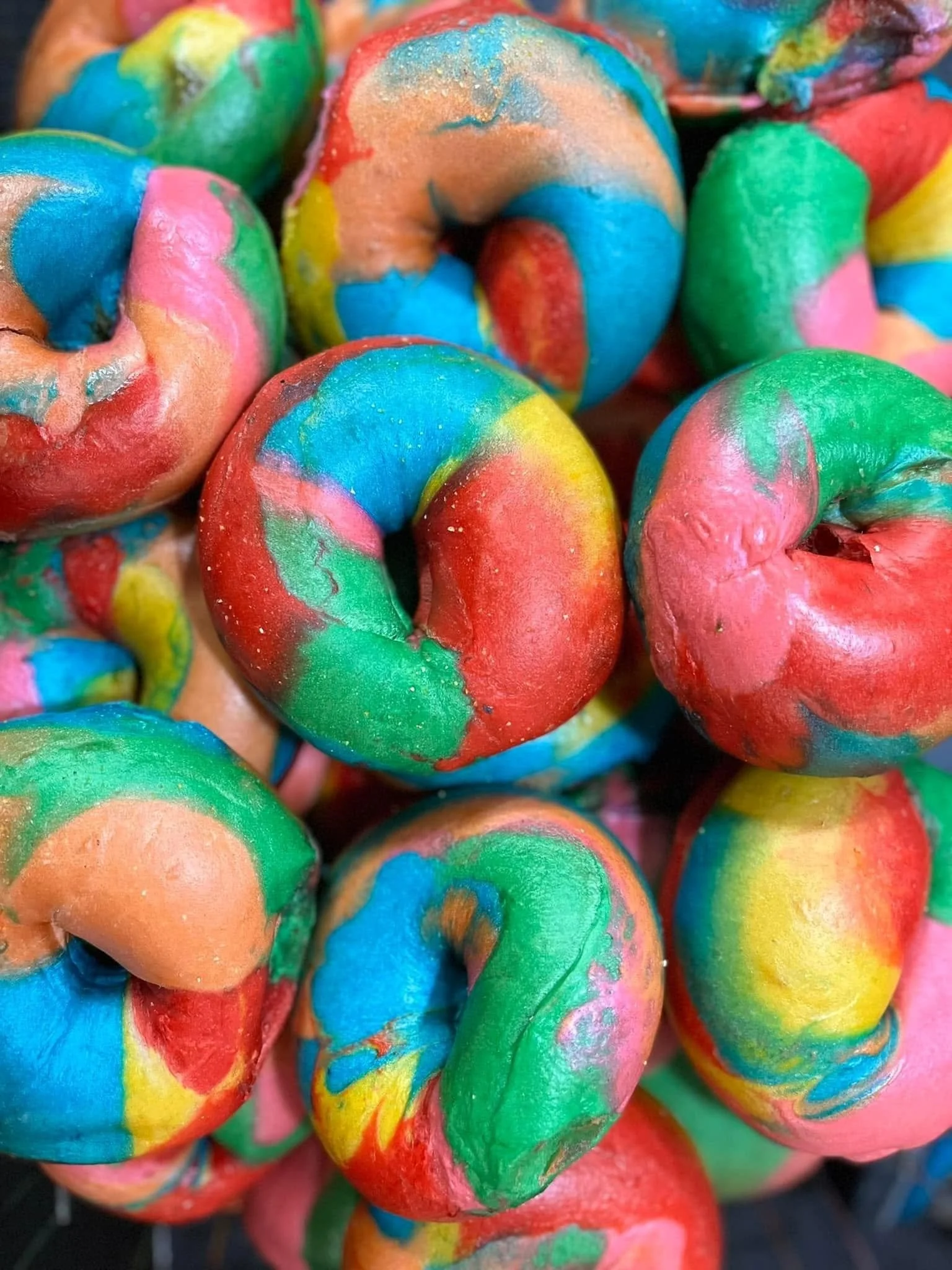 Colorful rainbow-colored bagels with swirls of blue, green, yellow, pink, orange, and red.