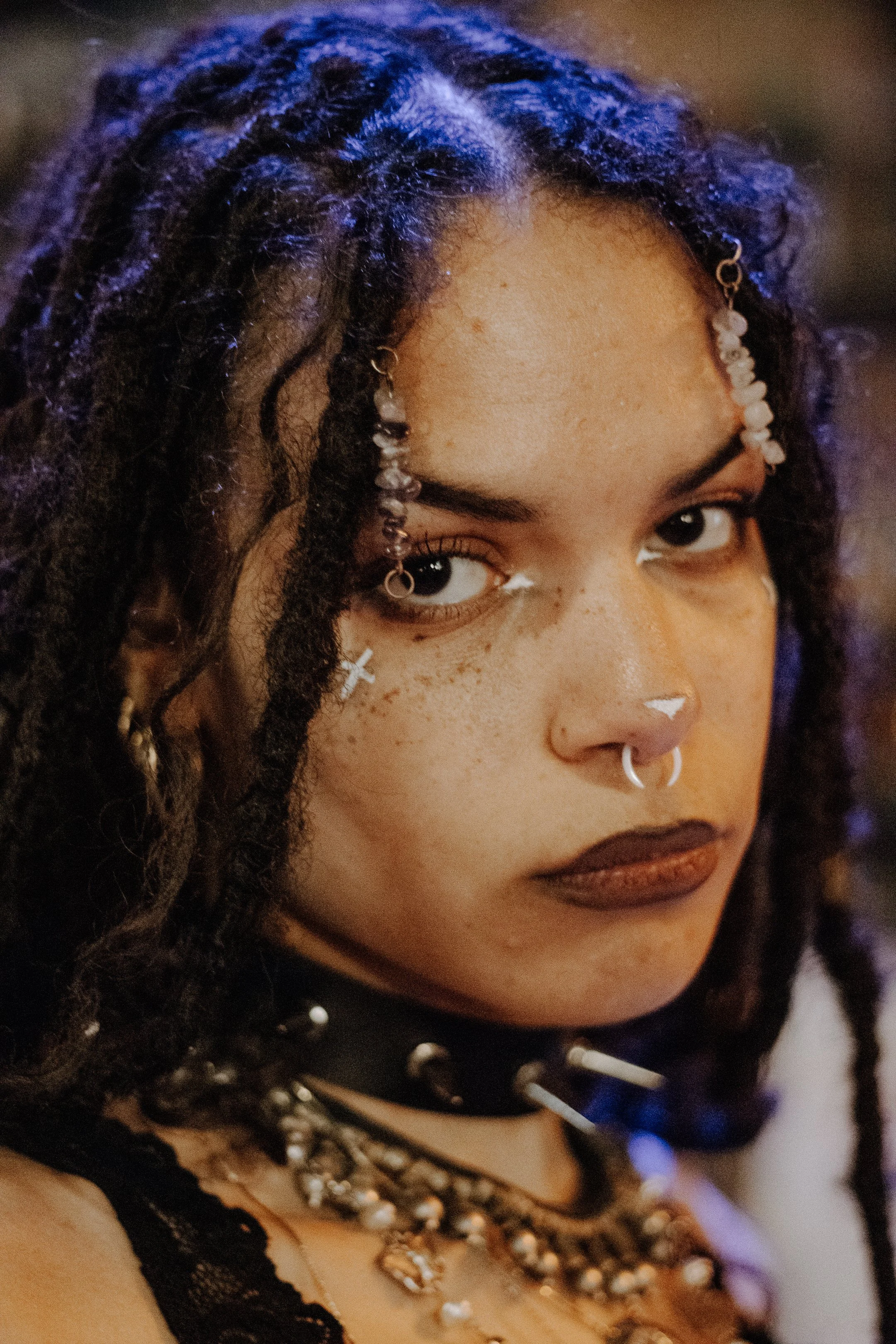 Tight portrait, long dark hair and a nose ring, direct unflinching eye contact