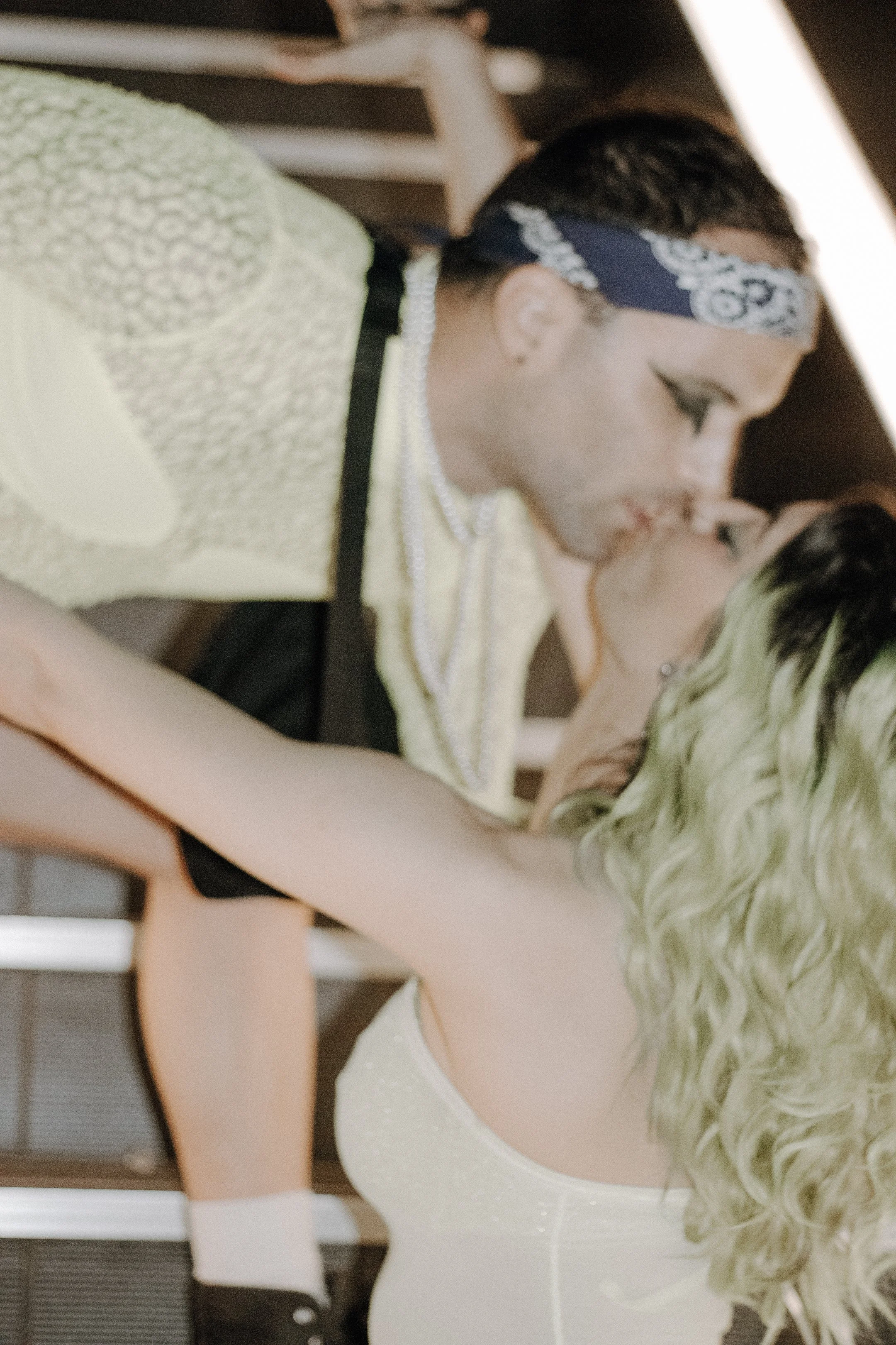 Two performers locked in an embrace on the stairs, one in a bandana leaning in close