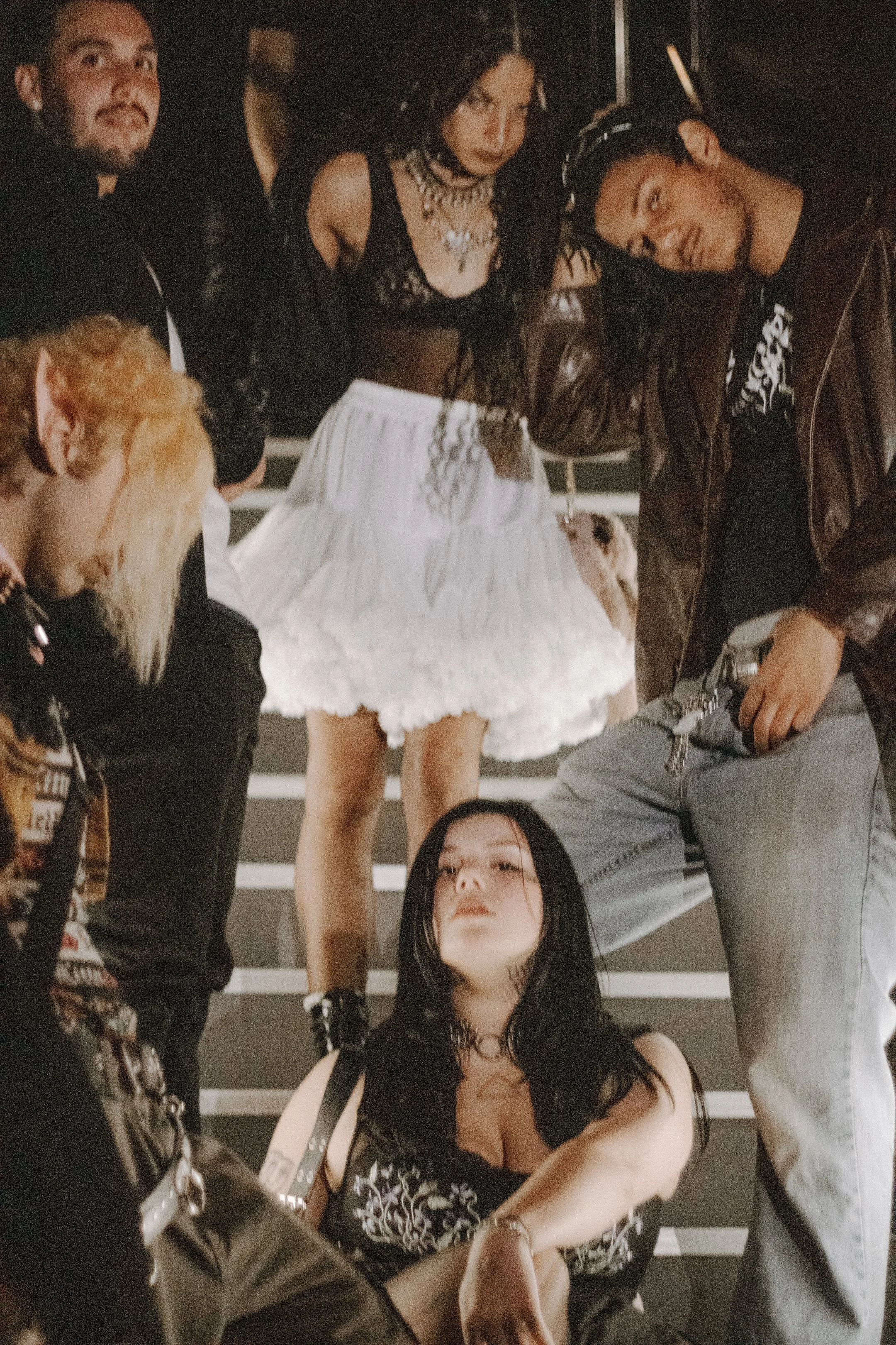Group of performers posed together on the stairs, one in a white tutu at center