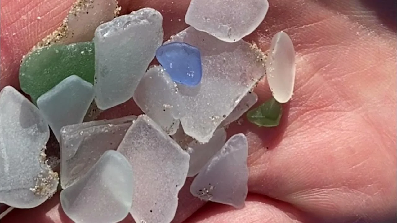A hand holds green, blue, and clear beach glass in a still from the short film Beach Glass.