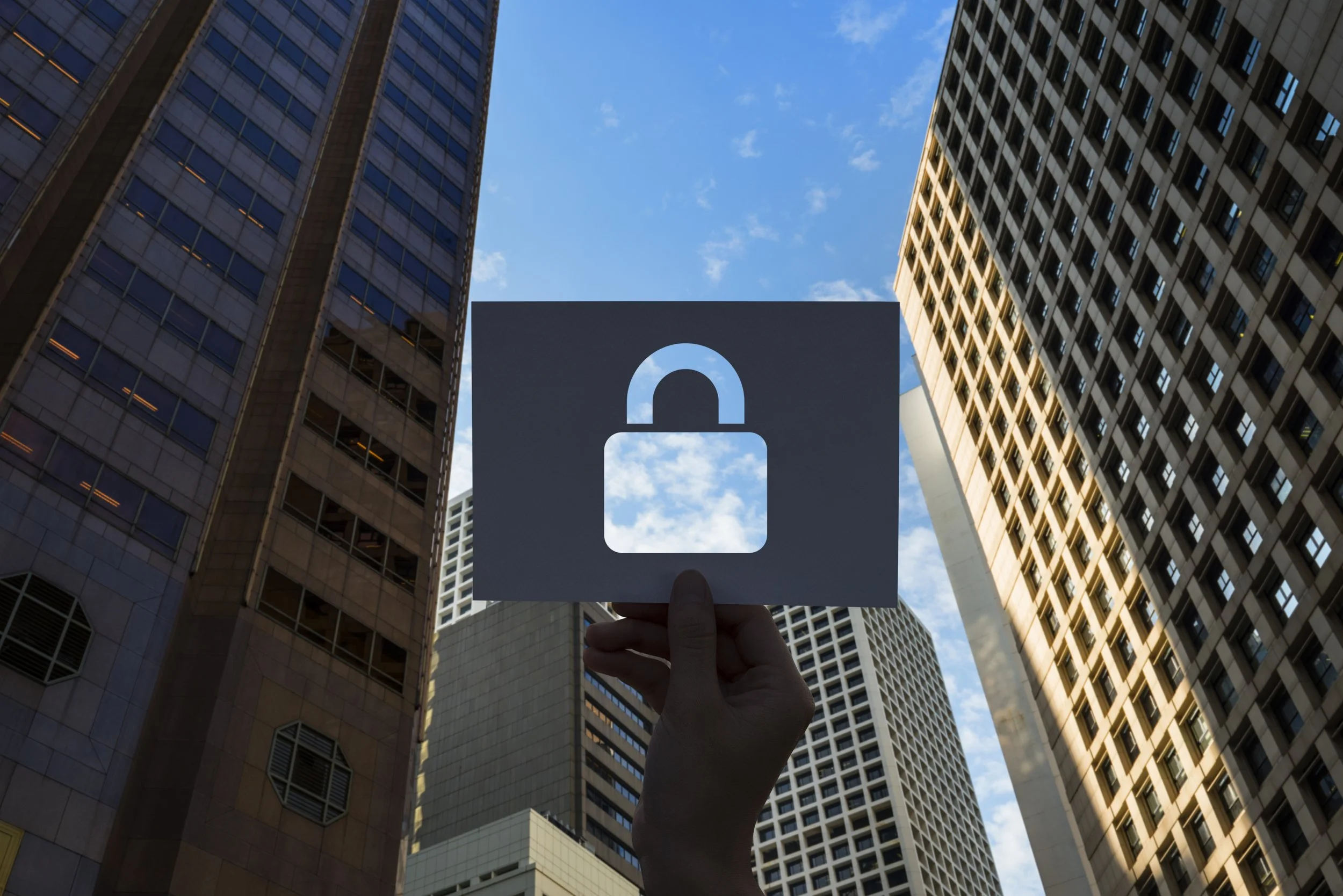 Person holding a sign with a padlock symbol in a city setting, representing cyber security, data protection and privacy.