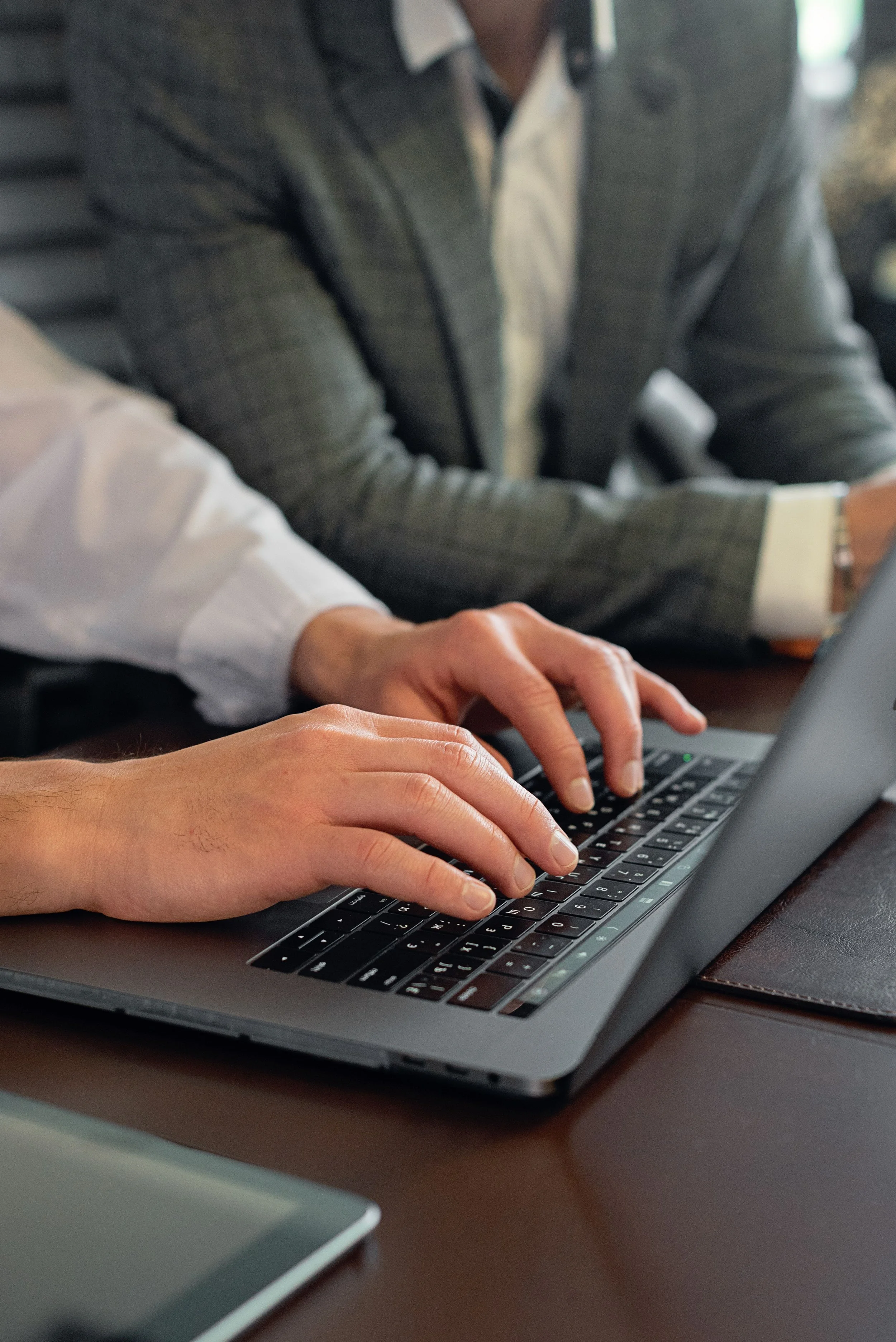 Two business professionals working together on a laptop, reviewing information on screen in a modern office environment.