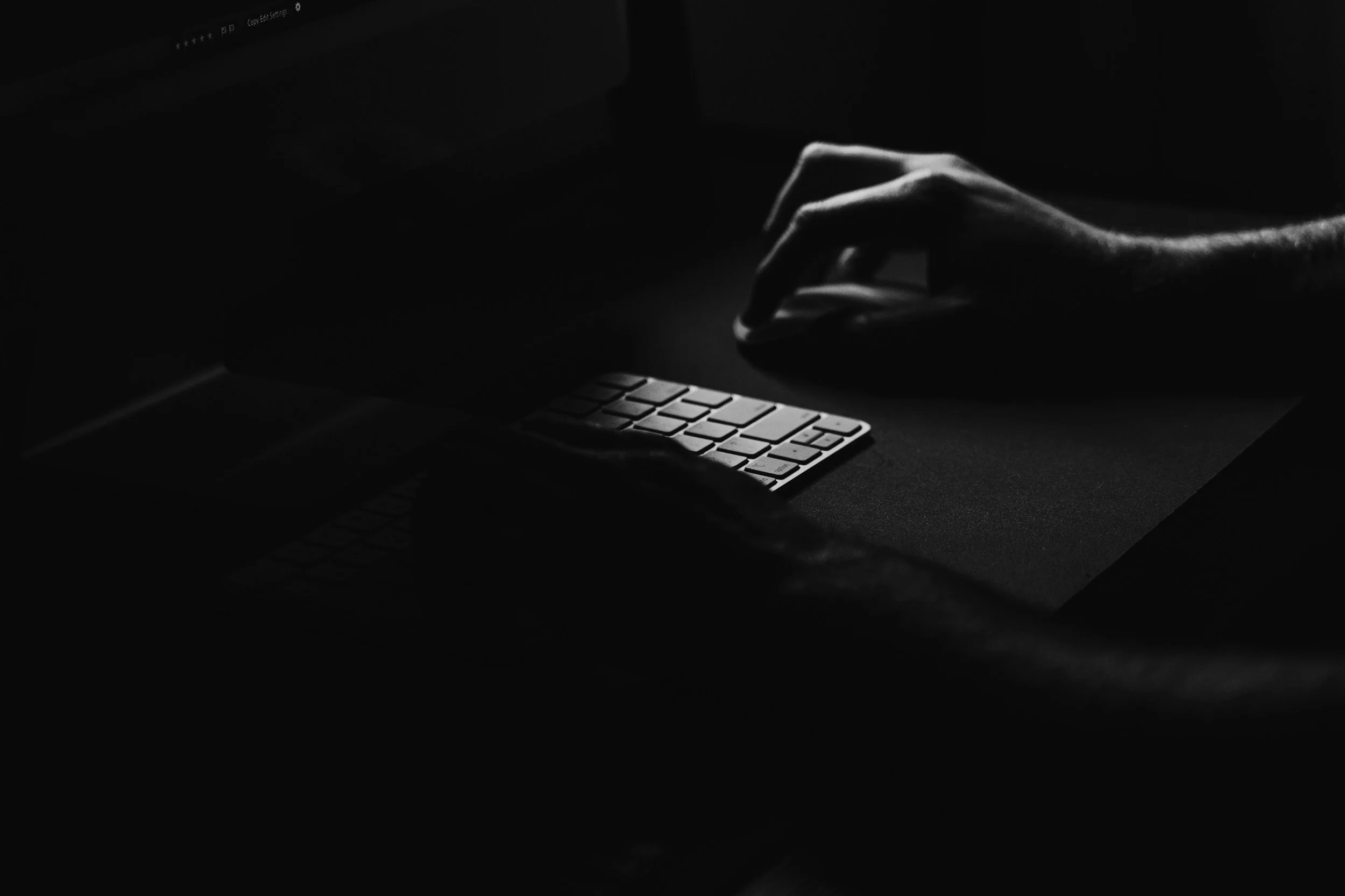 Person using a computer in a dark environment, representing the importance of cyber security, digital threats and online protection.