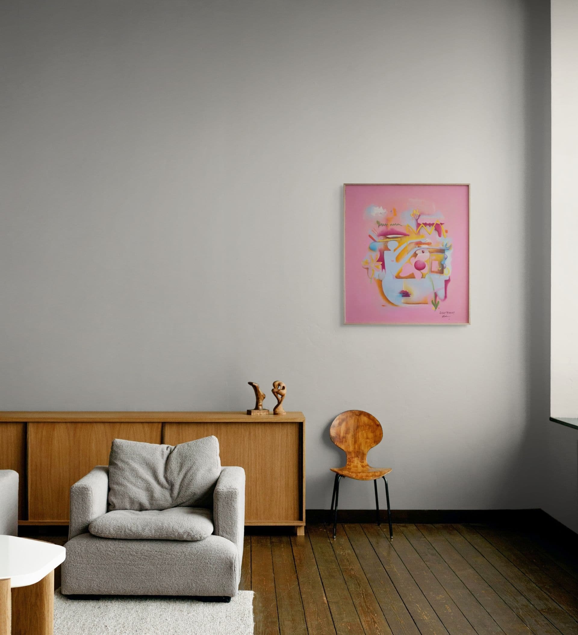Living room with a gray couch, a wooden sideboard, abstract artwork on the wall, a wooden chair, and hardwood floors.