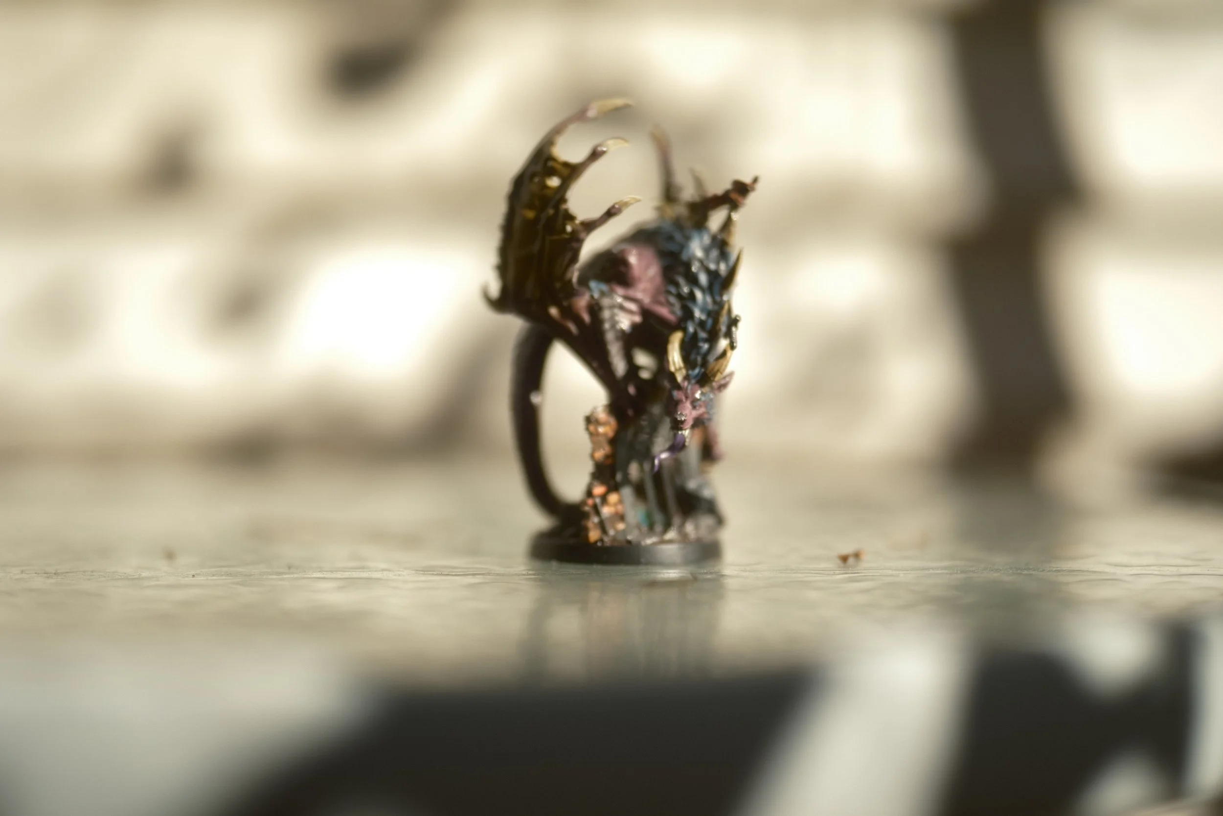 Miniature figurine d'un guerrier ou un personnage fantastique, très détaillée, positionnée sur une surface plane.