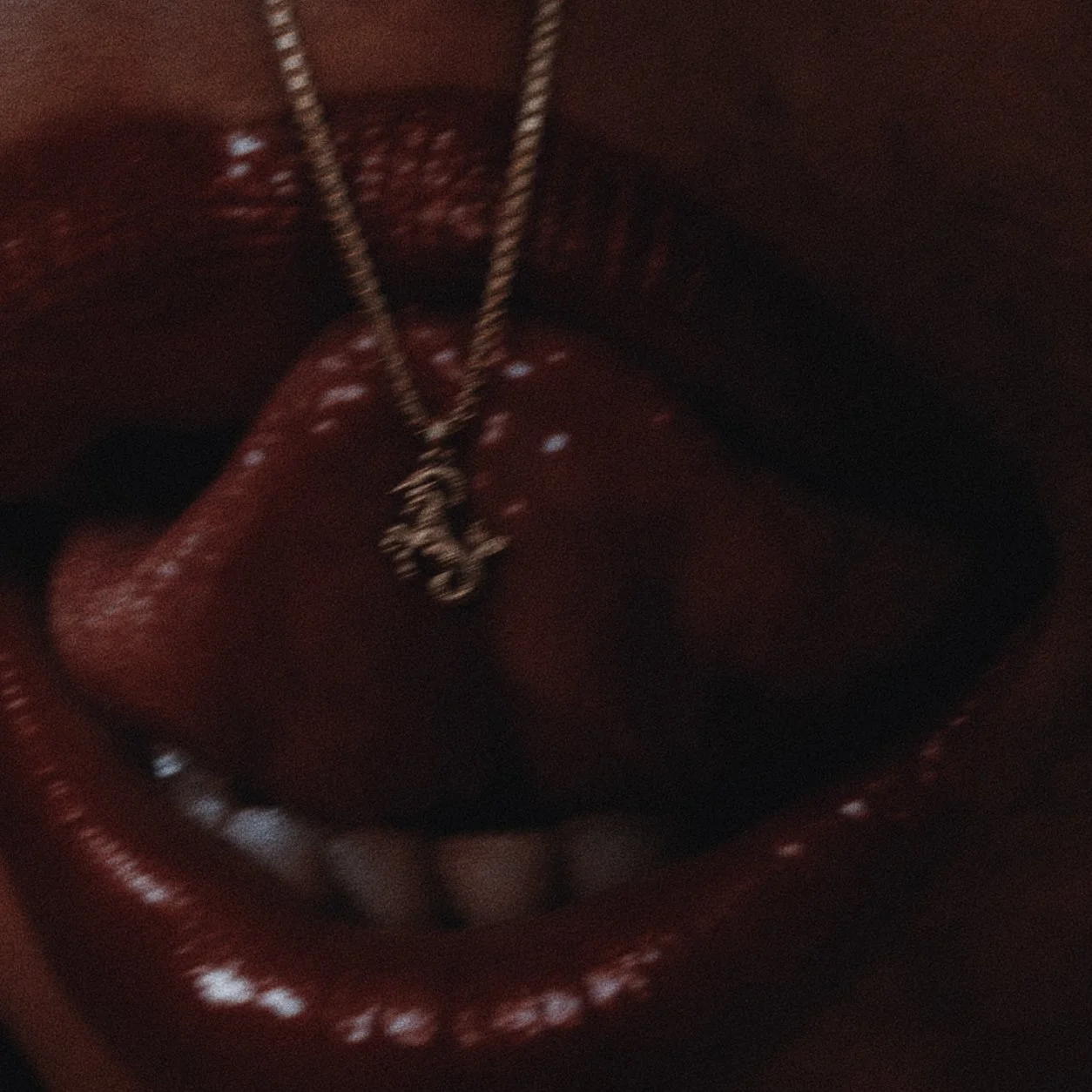 A close-up of a red leather jewelry box with a gold chain and pendant inside.