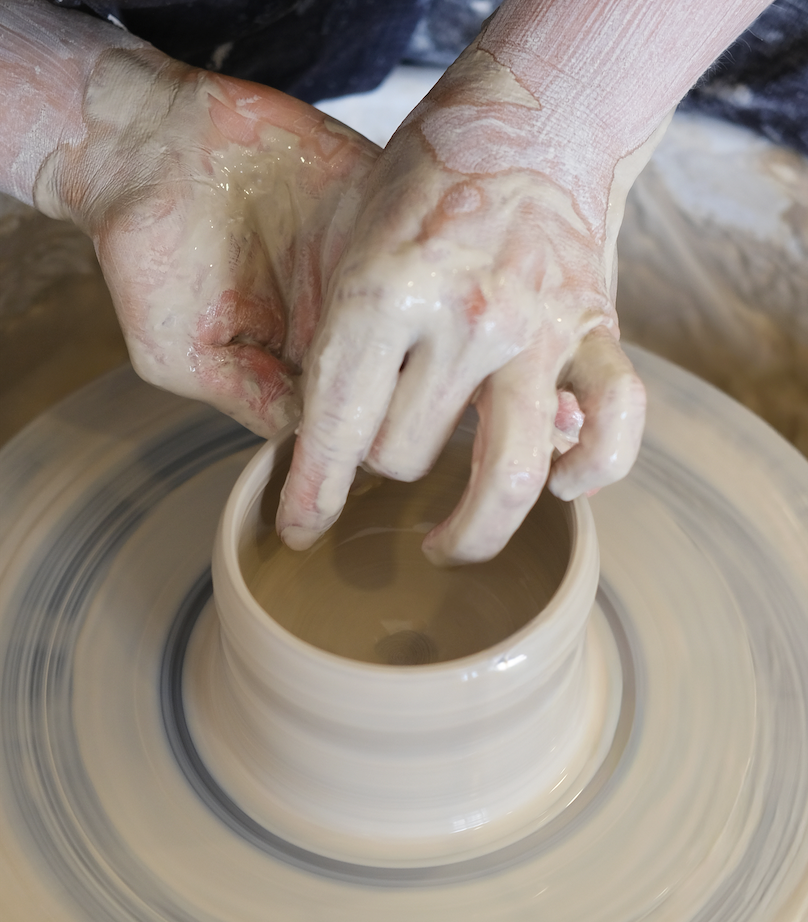 Main qui façonne de la poterie sur un tour de potier.