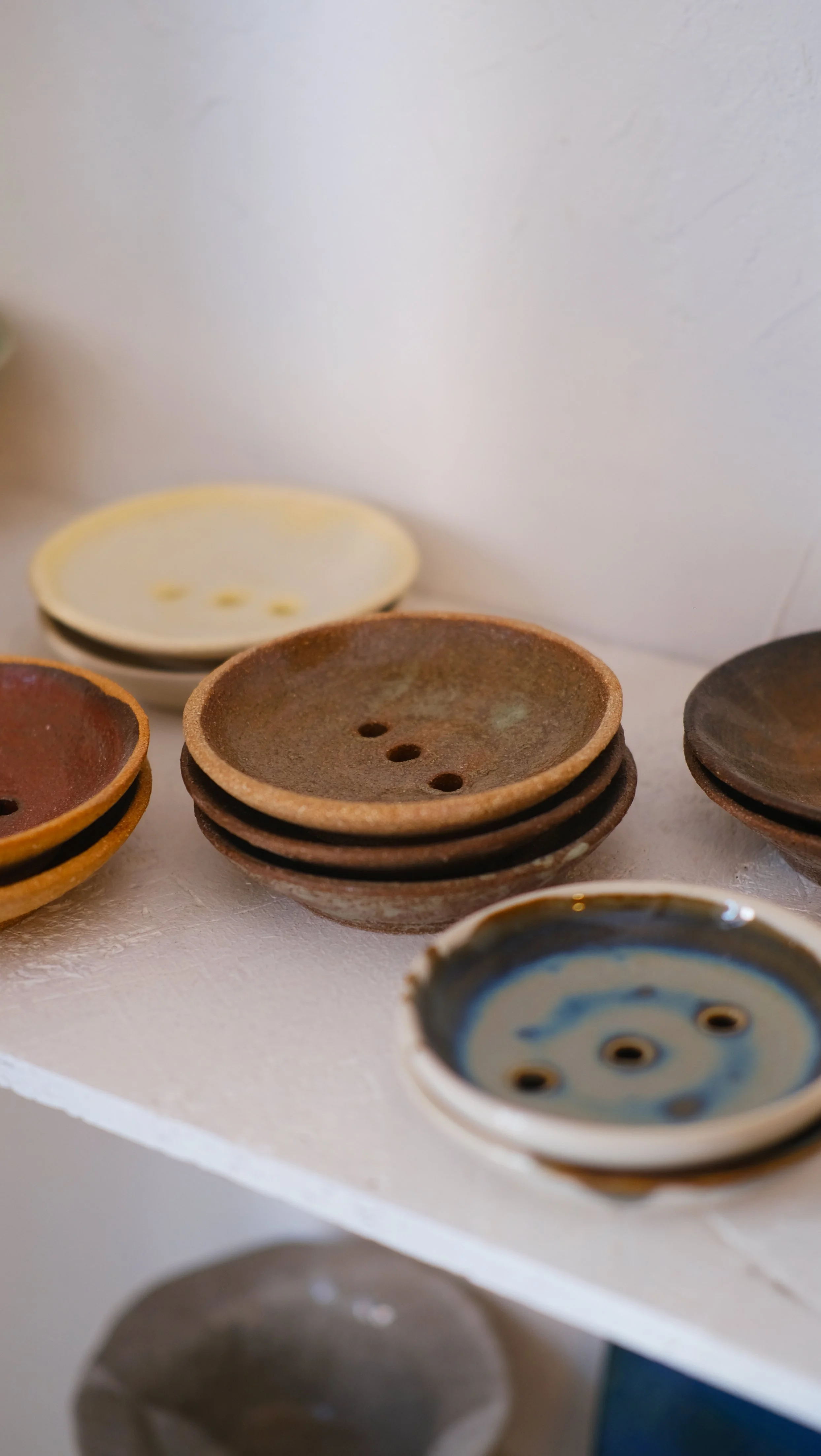 Une collection de boutons en céramique de différentes tailles et couleurs, posés sur une surface blanche.