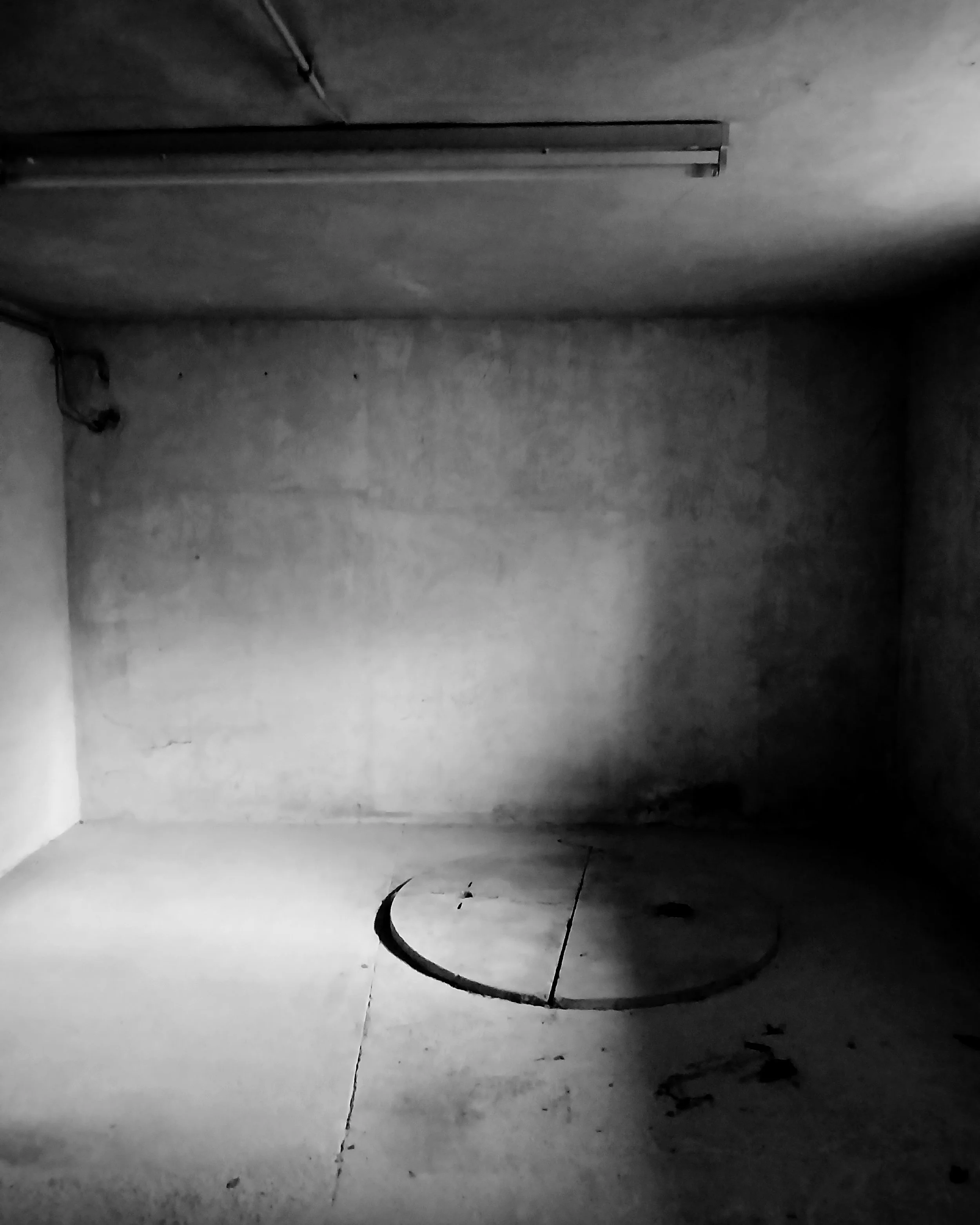 A dark, abandoned basement. On the floor there is a circular opening to an unknown underneath. The atmosphere is unsafe and oppressive.