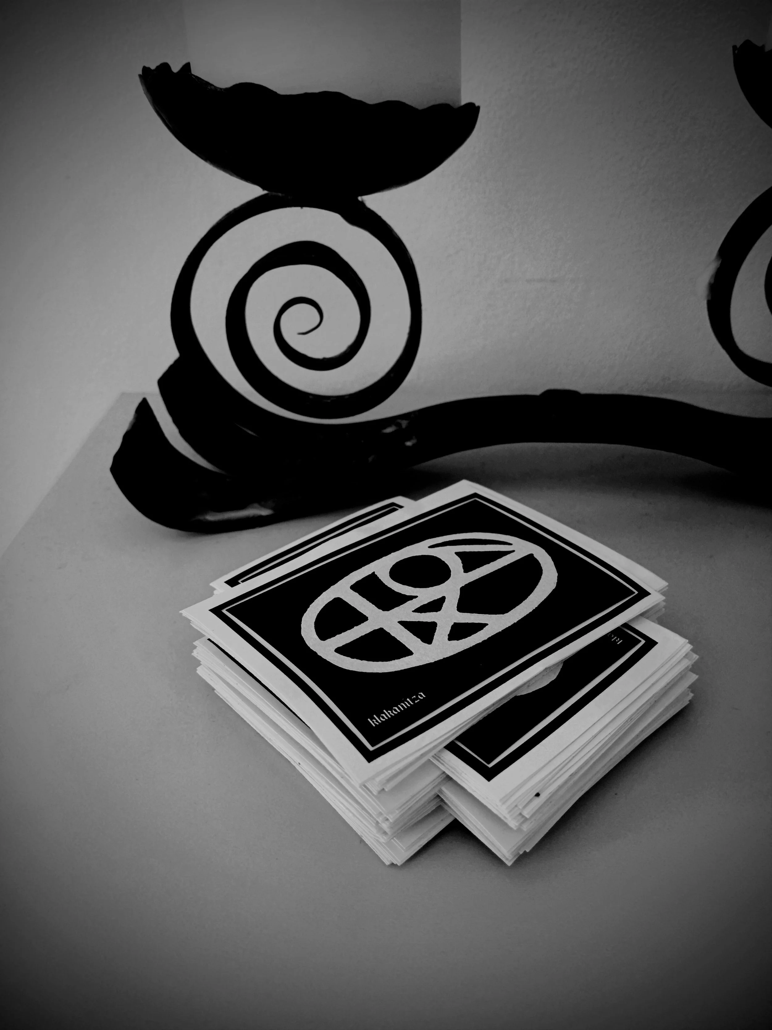 A stack of black and white stickers featuring a sigil and the work "klakanitza".