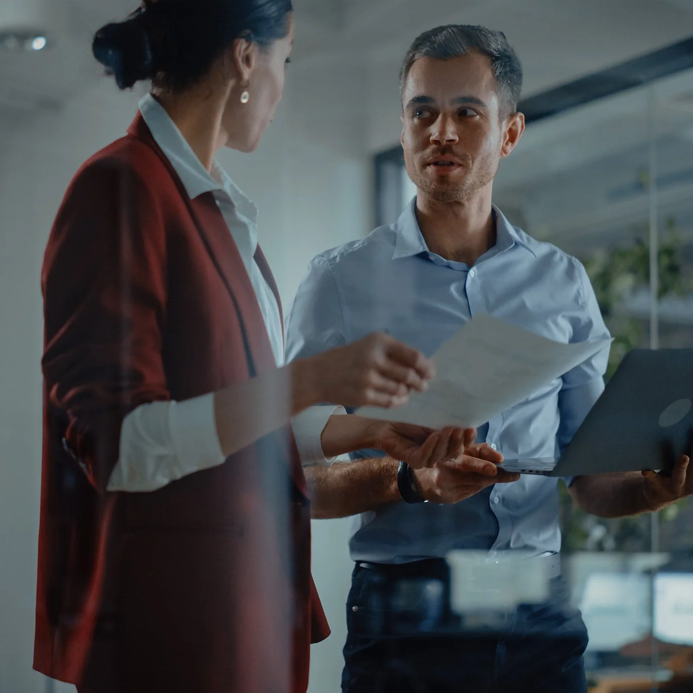 Business colleagues discussing documents and a laptop in a modern office