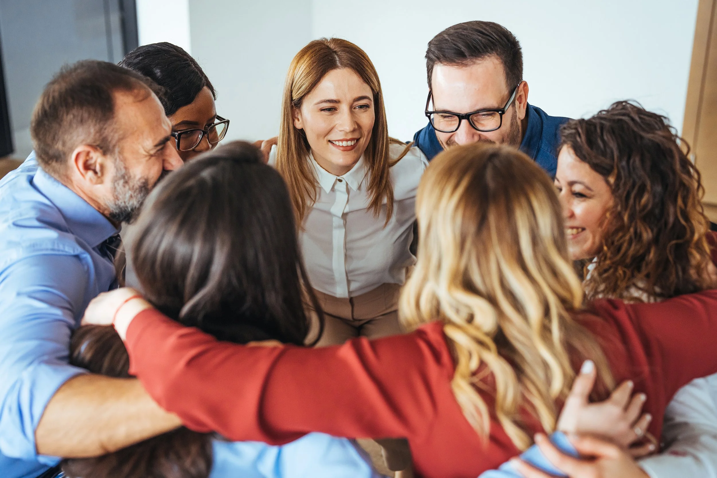 Diverse group of coworkers smiling and embracing in a team huddle