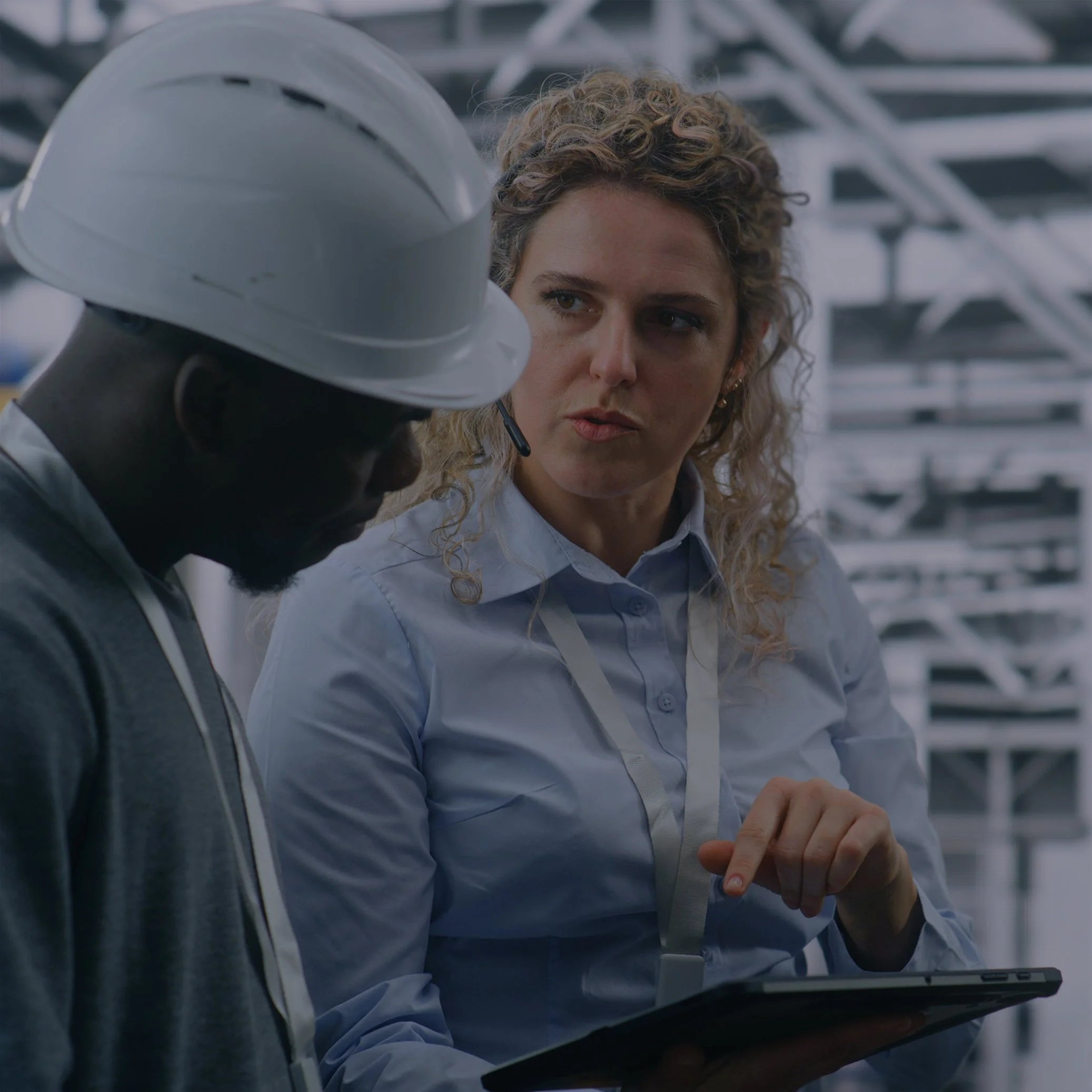 Female engineer wearing a headset and holding a tablet inside an industrial facility