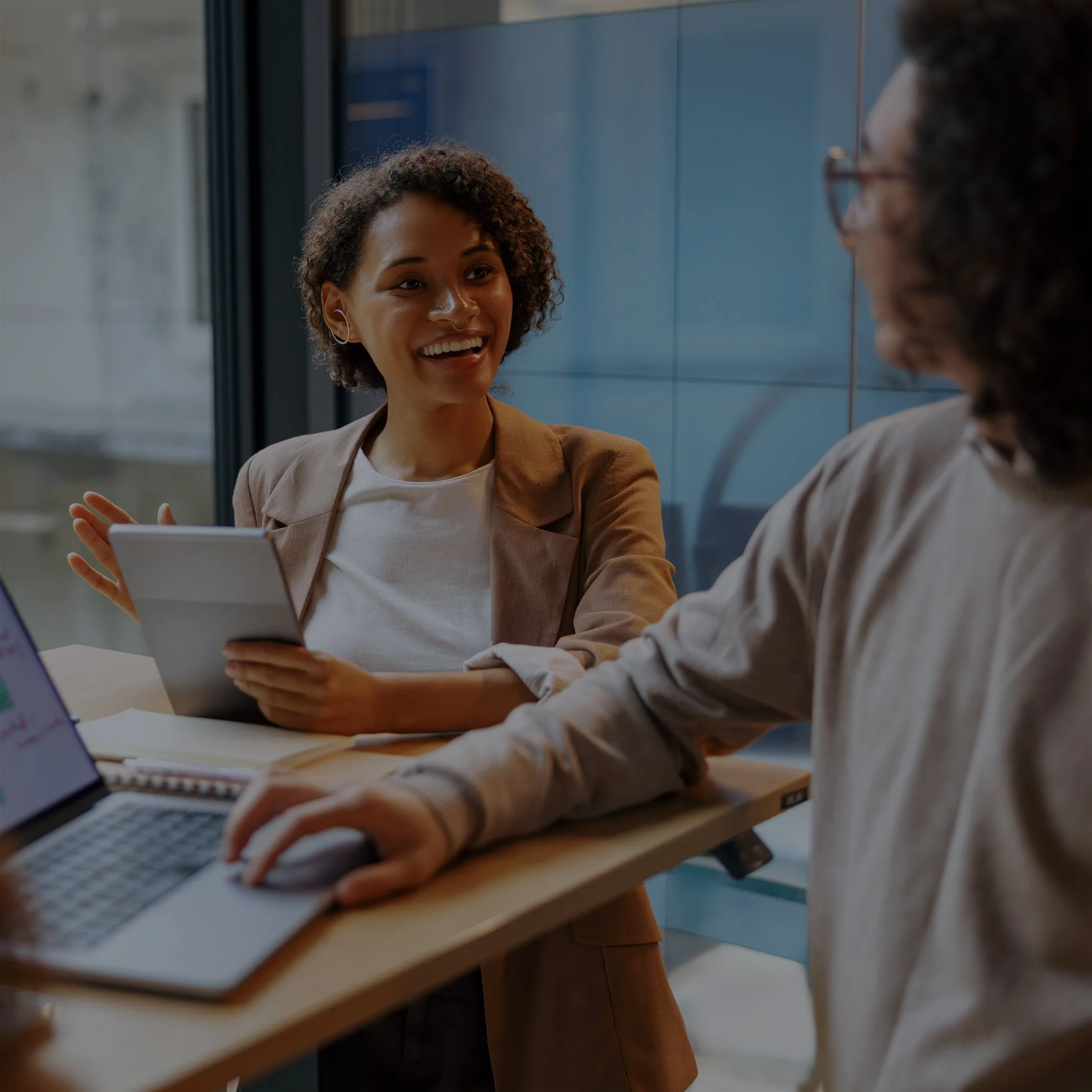 Diverse business team collaborating around a table with a tablet and laptop in a modern office