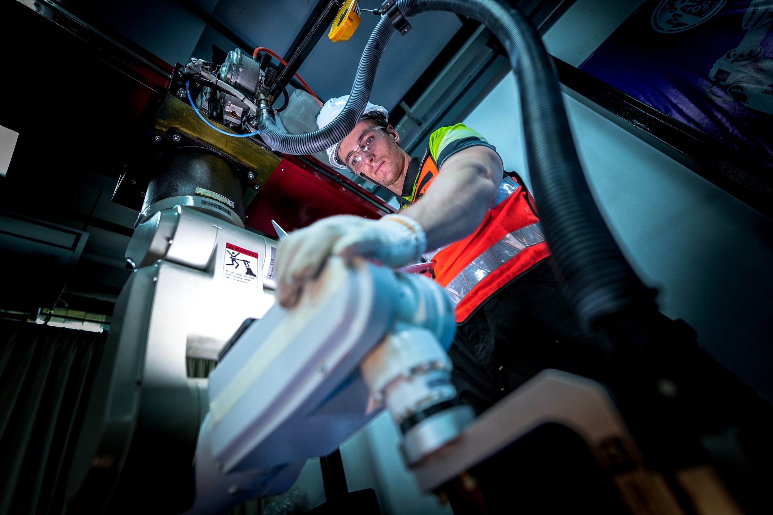 Industrial worker in safety gear inspecting machinery and hoses from a low angle