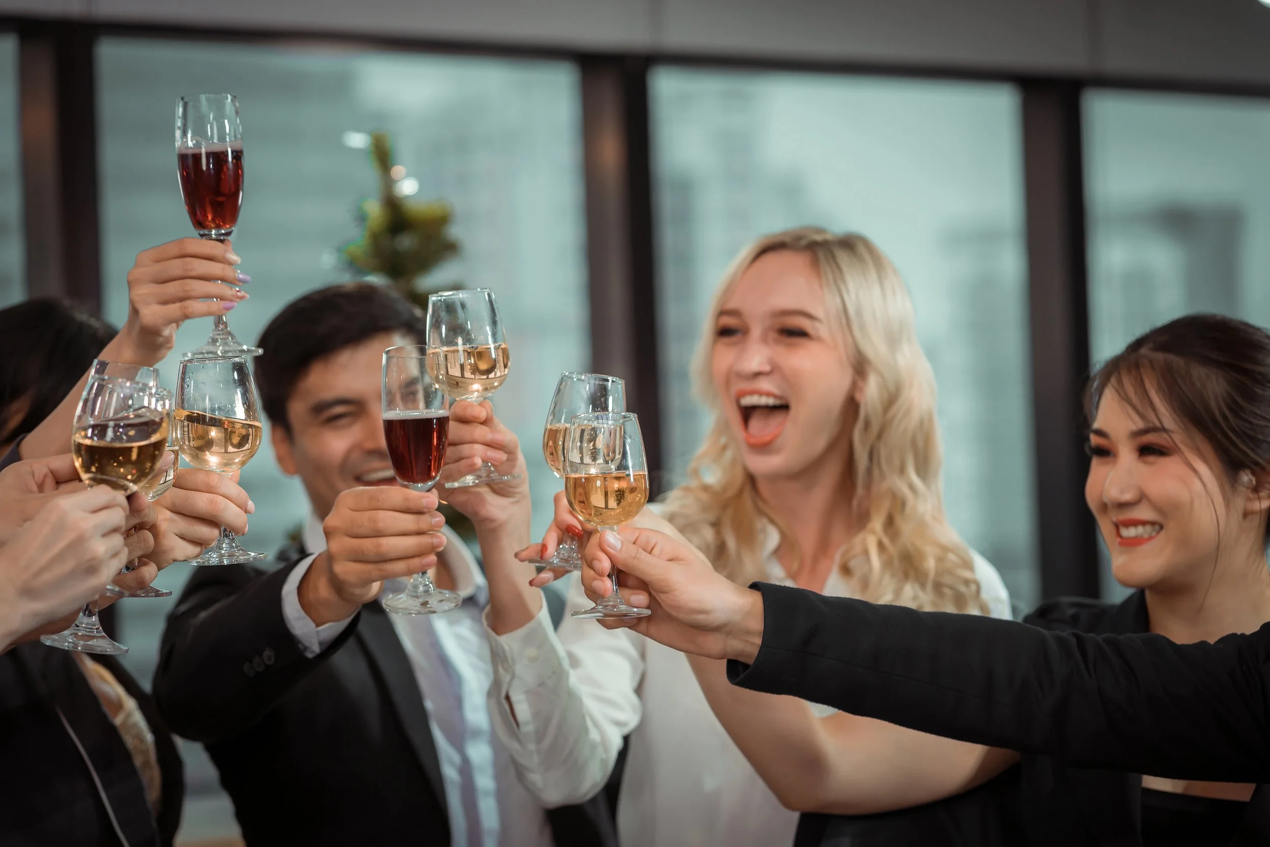 Group of friends laughing and raising glasses of wine in a celebratory toast