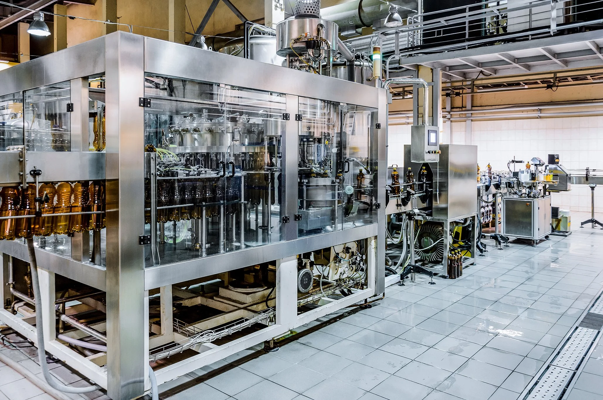 Industrial bottling machine filling brown glass bottles on a beverage production line