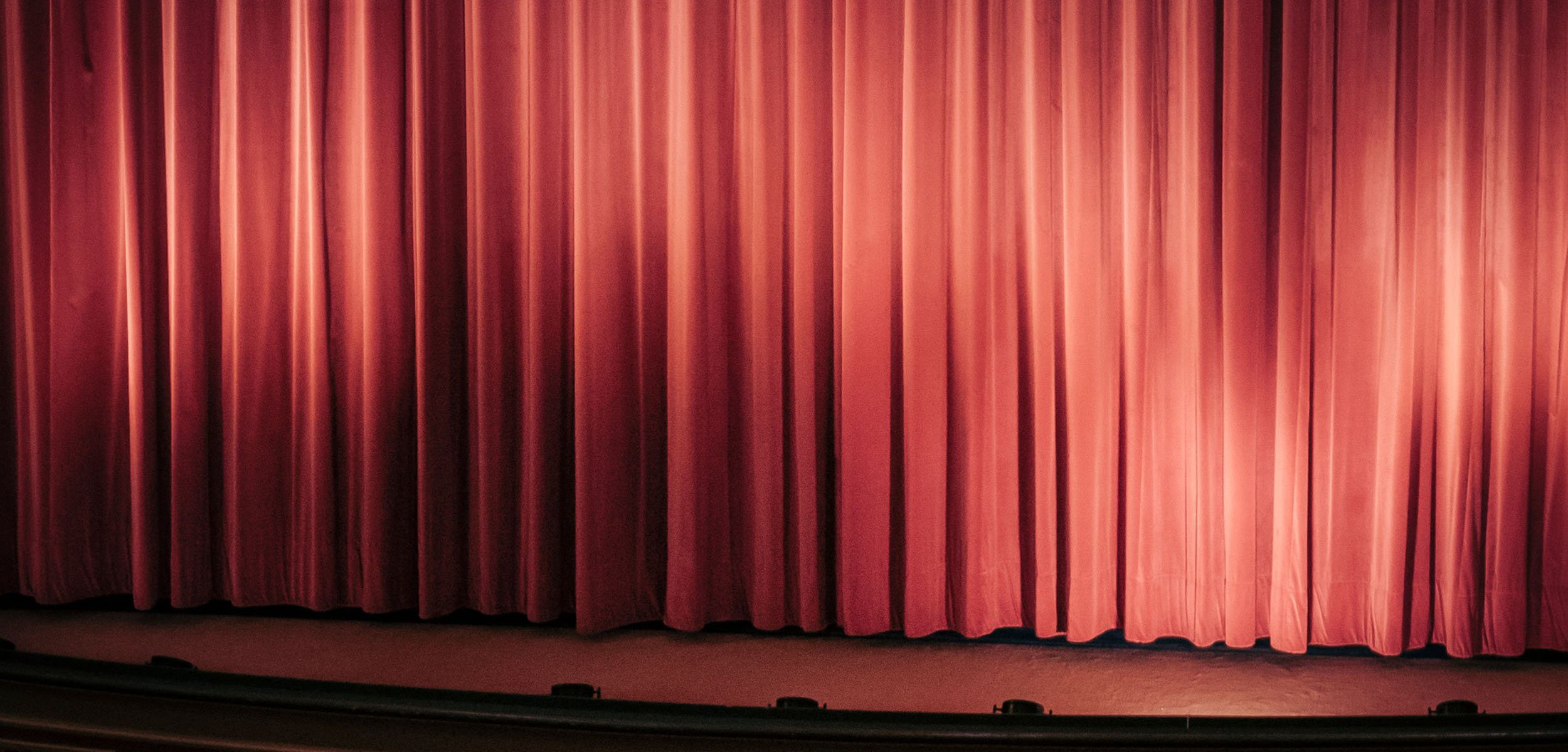 Closed red theater curtains on stage.
