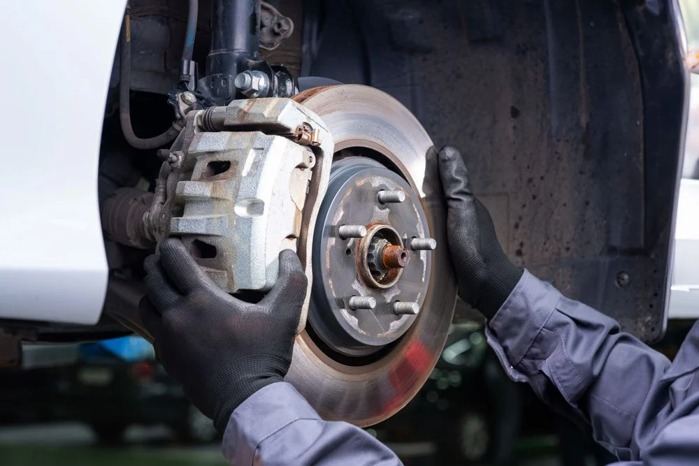 A mechanic installing a new brake rotor on a vehicle's wheel hub.