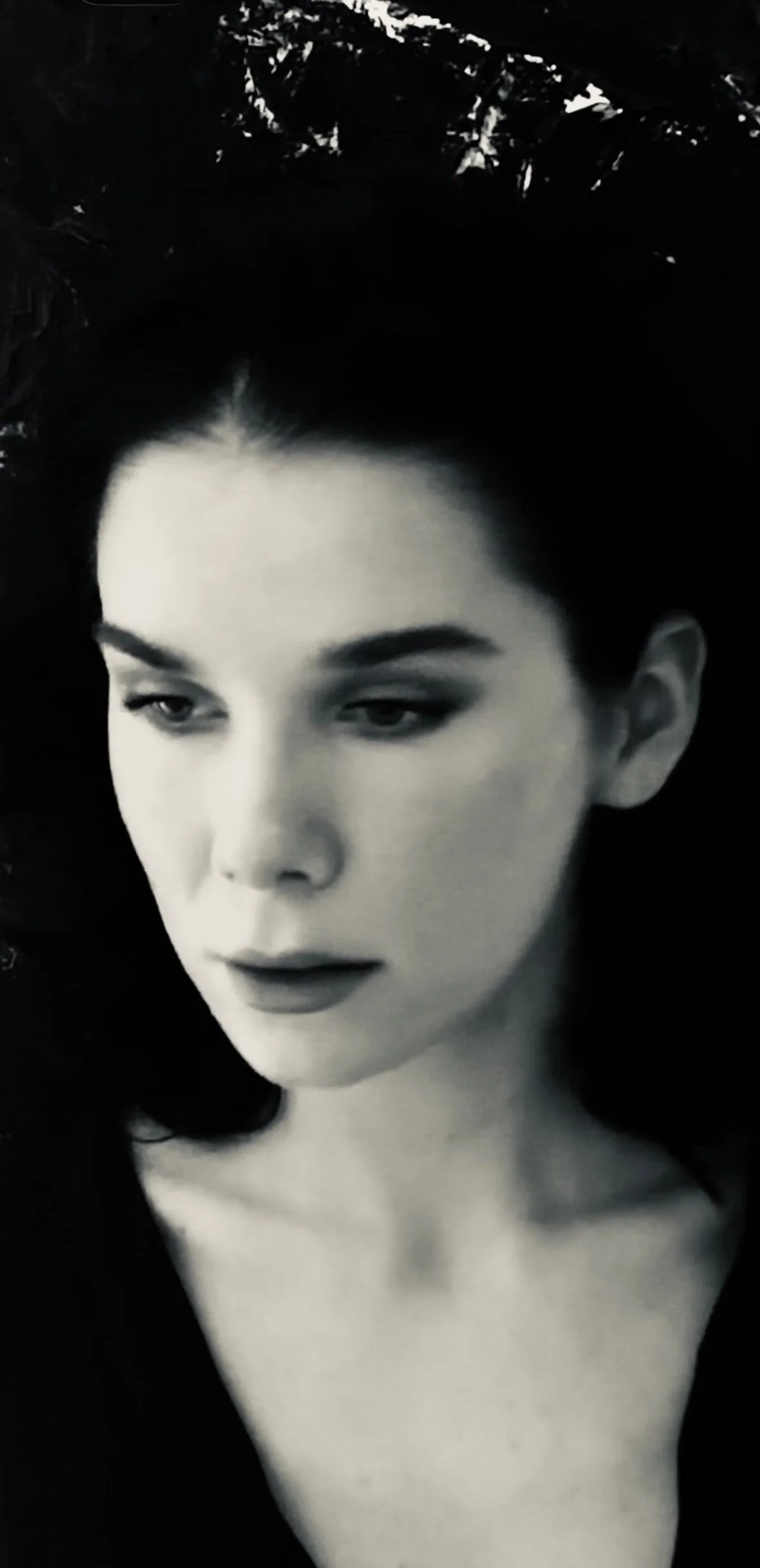 Black-and-white close-up portrait of a woman with short dark hair and dramatic eye makeup