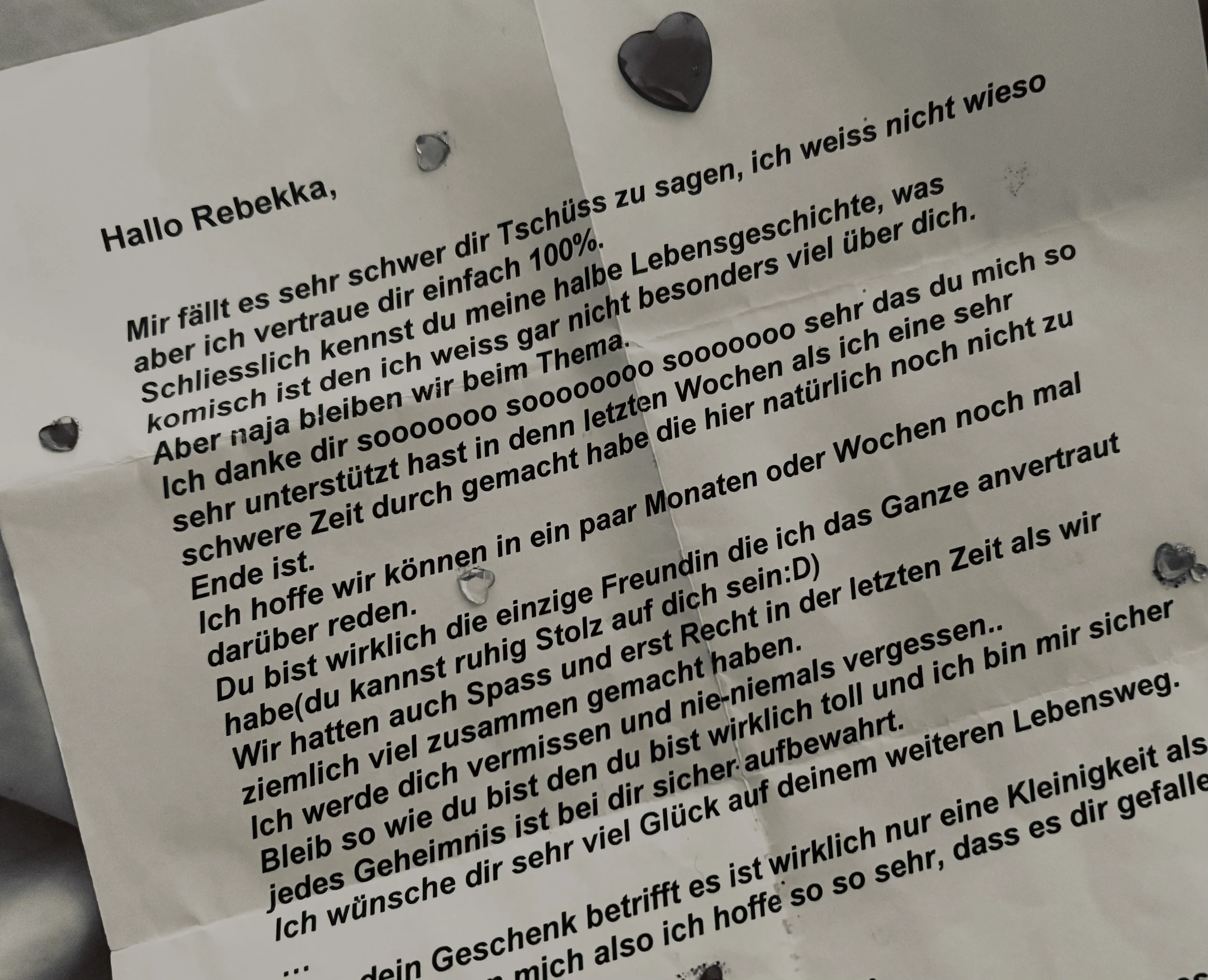 Close-up of a handwritten-style German farewell letter addressed to Rebekka, decorated with heart-shaped stickers.