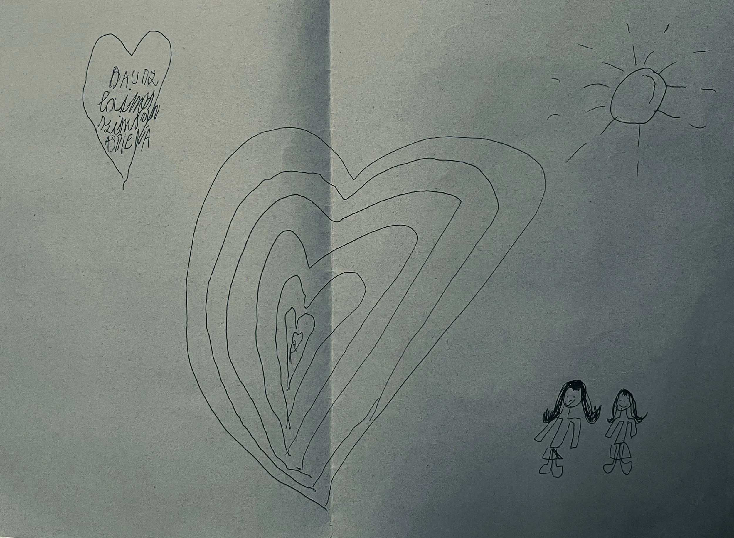 Hand-drawn picture of a large heart-shaped balloon with a small heart and two girls underneath, plus a smiling sun and a heart-shaped note reading “Laura, Las mejores amigas.”