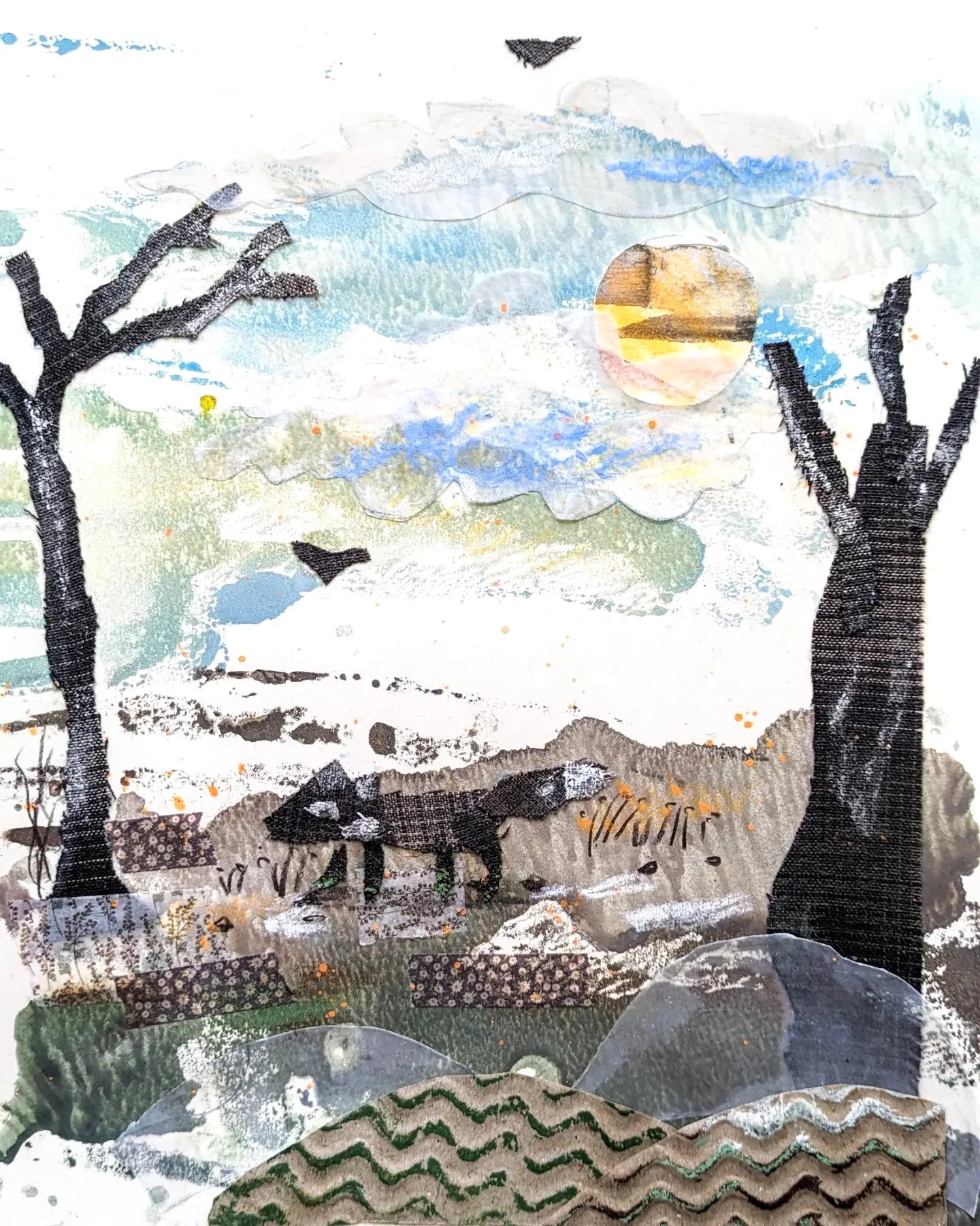 A collage artwork depicting a sunset over a landscape with trees, mountains, a river, and animals like a deer and birds, created with various textured fabrics and patterns.