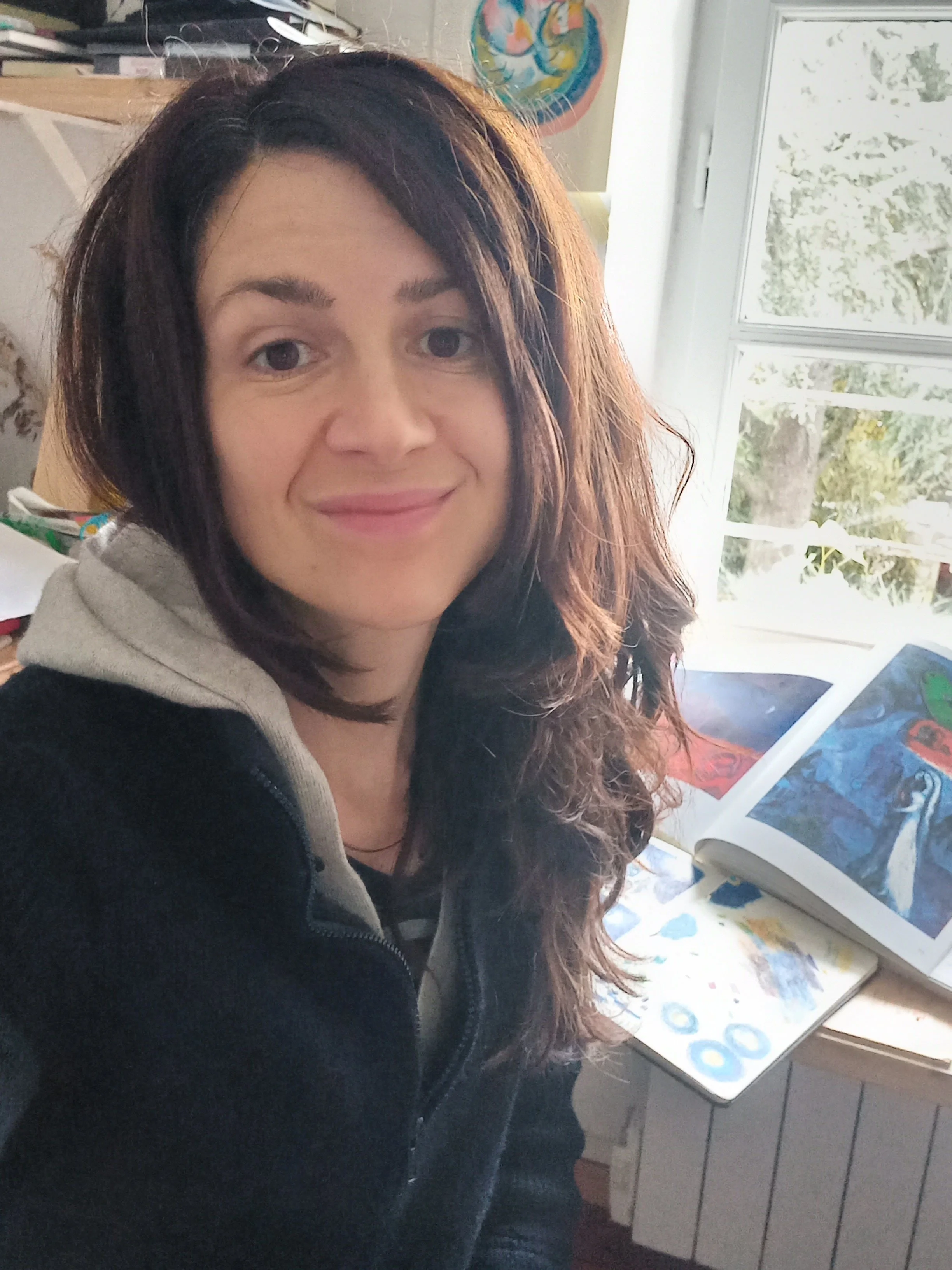 EN — Laura Humphris, artist and illustrator, in her studio surrounded by paintings and drawings.

FR — Laura Humphris, artiste et illustratrice dans son atelier, entourée de peintures et de dessins.