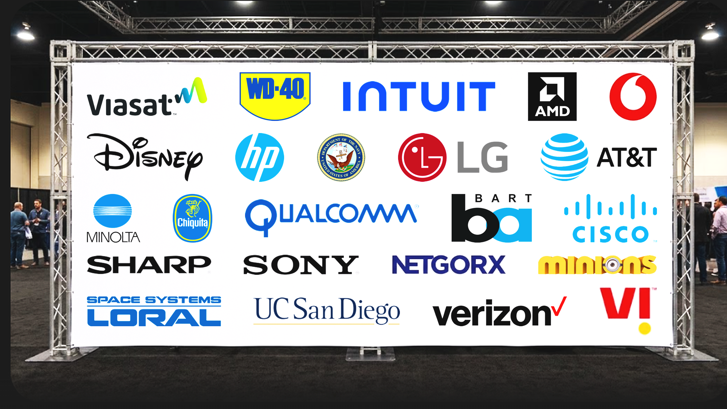 A display board showing logos of various technology and corporation companies at an event, including Viasat, WD-40, Intuit, AMD, Disney, HP, U.S. Navy, LG, AT&T, Minolta, Chiquita, Qualcomm, Bart Ba, Cisco, Sharp, Sony, Netgors, Miions, Space Systems Loral, UC San Diego, Verizon, and V.