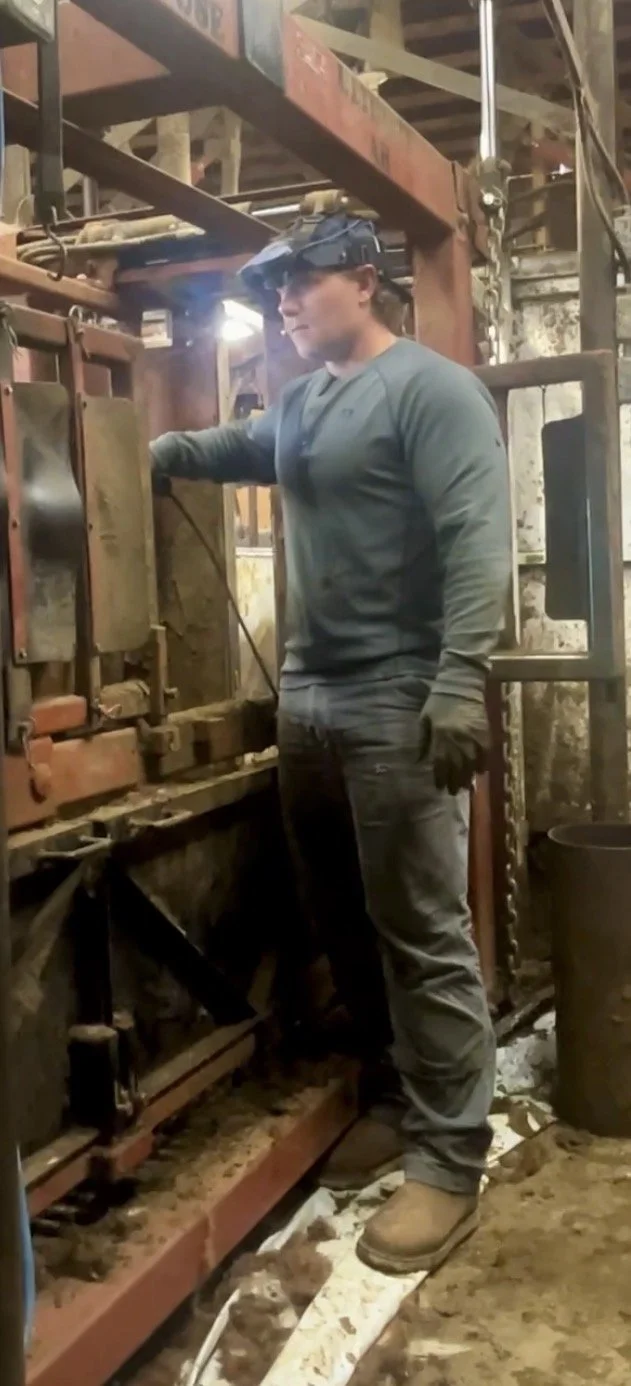 Worker wearing protective gear operates industrial machinery inside a metalworking facility.