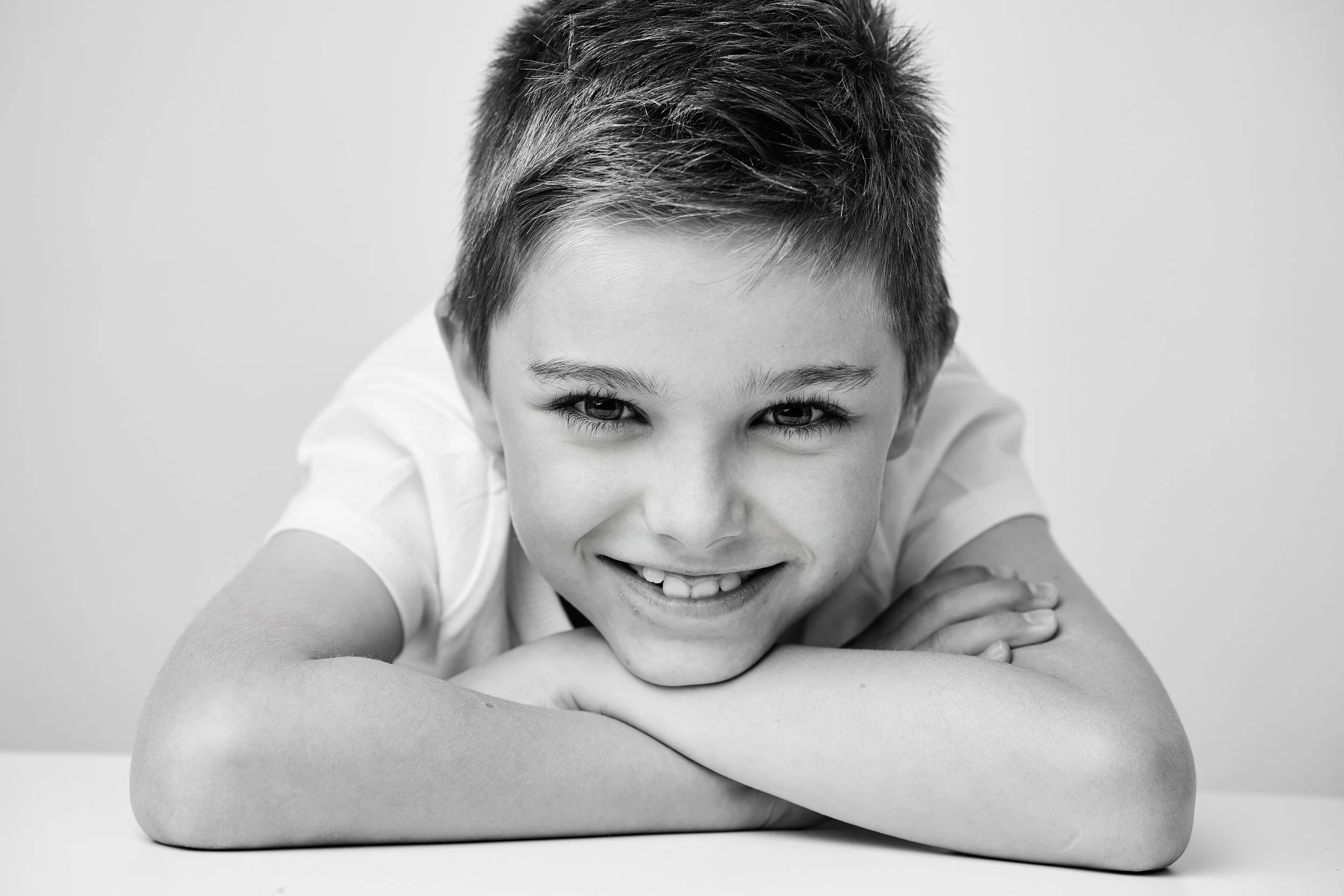 Beautiful black and white children's portrait capturing a natural smile and genuine personality. Timeless children's studio photography by Lucas Gudaniec Photography, creating treasured family memories for clients in Annecy and Geneva.