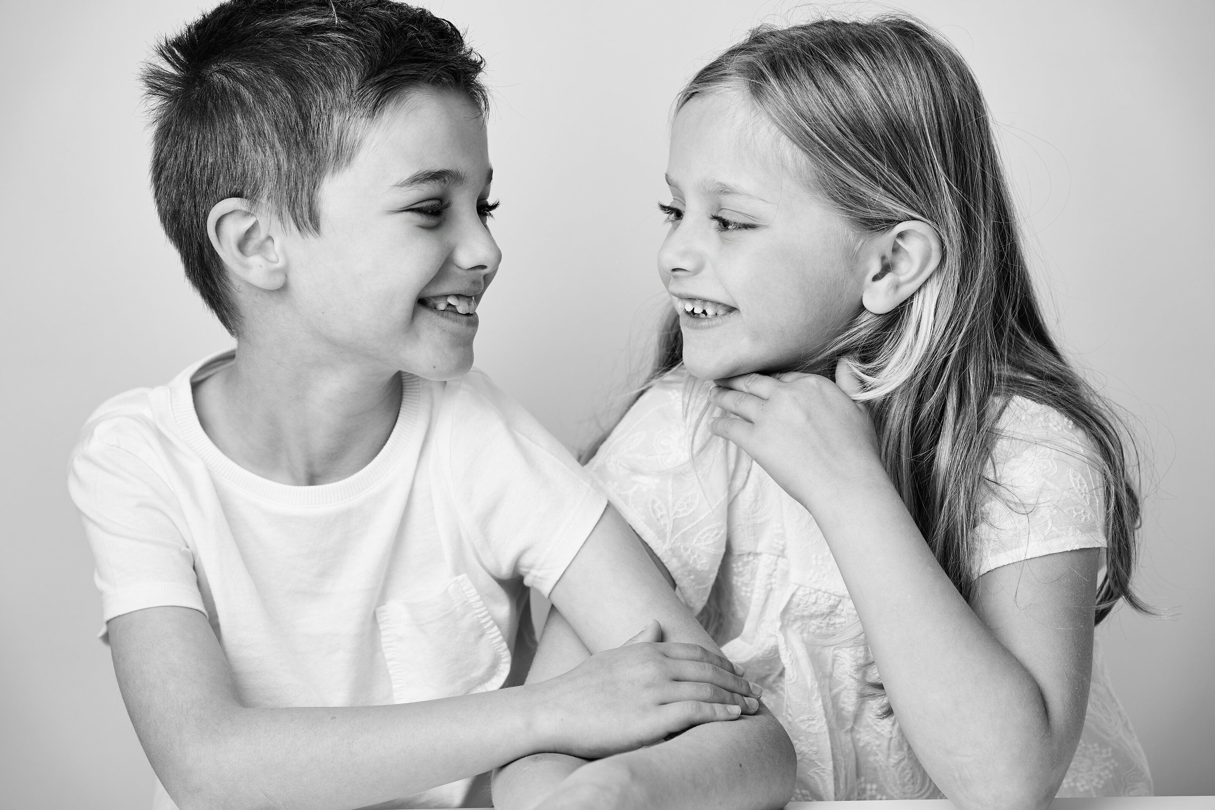 Timeless sibling photography capturing the genuine connection between brothers and sisters. Lucas Gudaniec Photography creates elegant black and white studio portraits for families in Annecy, Geneva and surrounding areas.